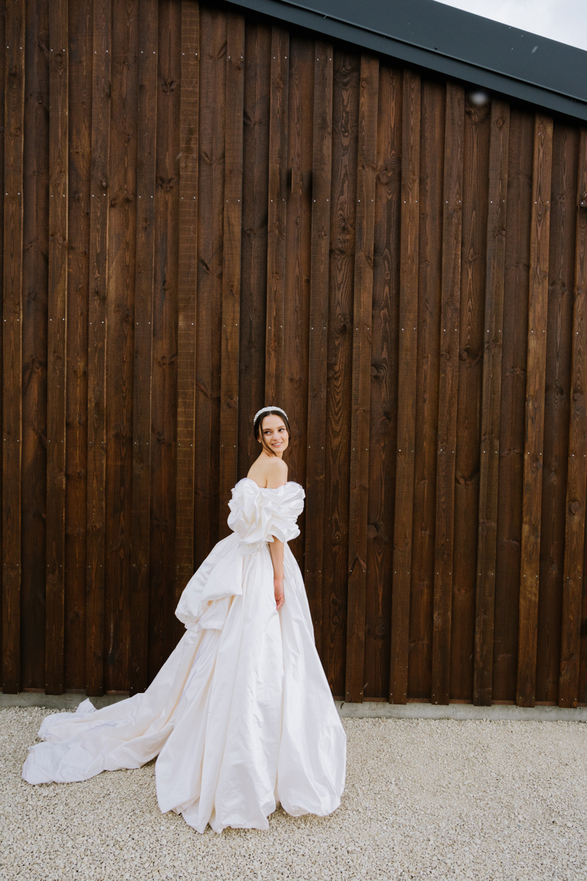 a woman in a white dress standing in front of a wooden fence