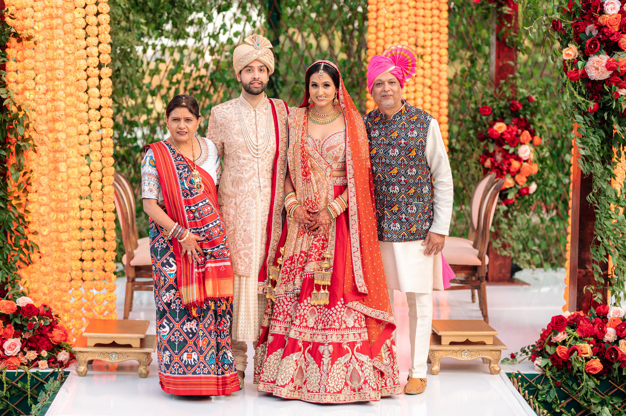 a bride and groom pose for a photo in front of a floral arch
