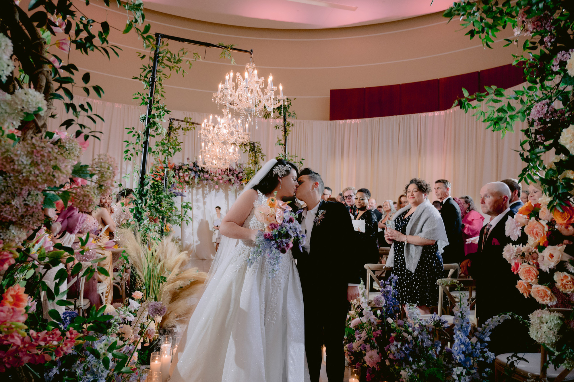 a bride and groom are standing in front of a floral arch