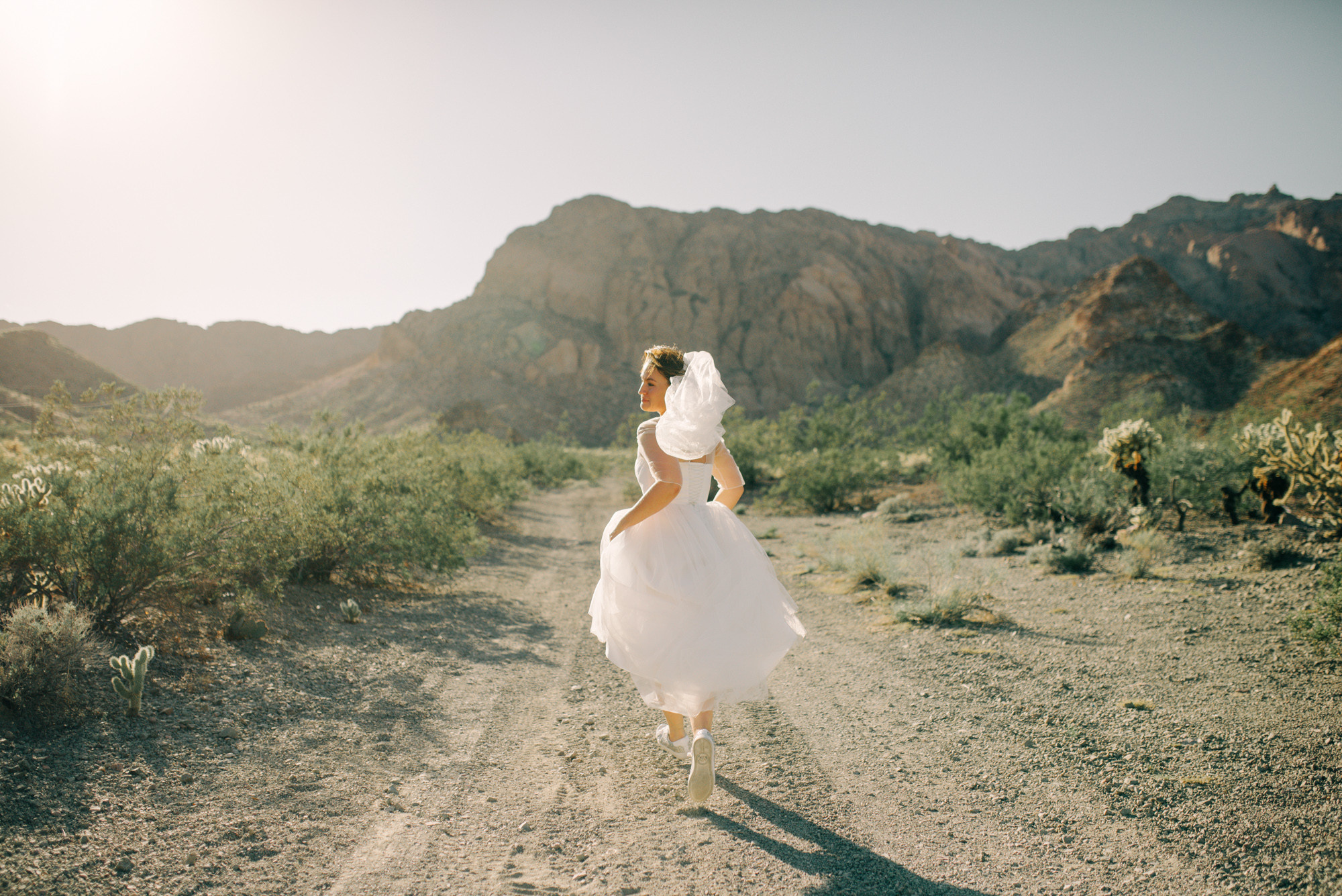 a woman in a white dress is walking down a dirt road