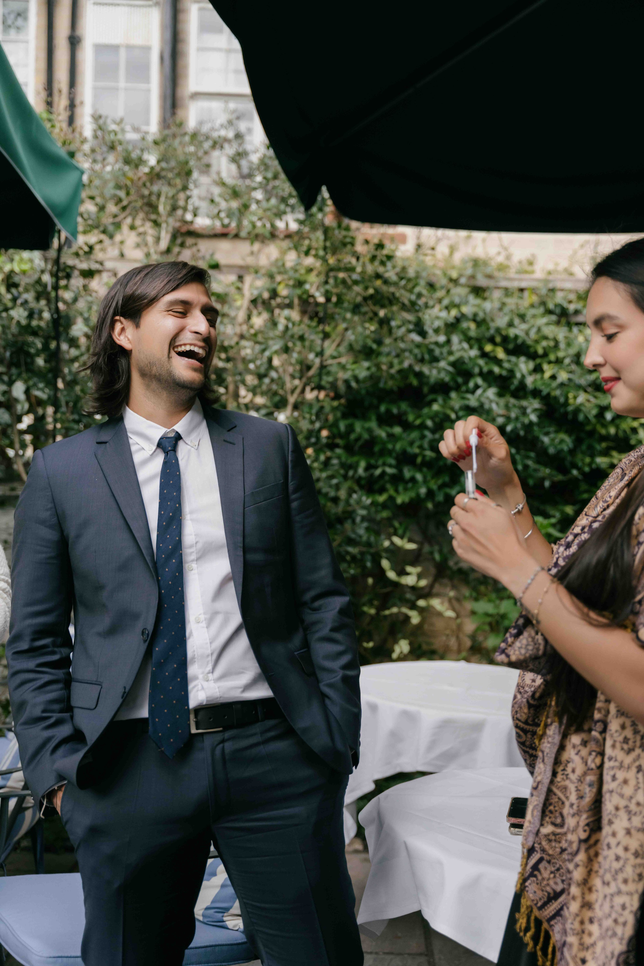 Wedding guests laughing during reception at The Ivy London, candid emotional moment, documentary wedding photography