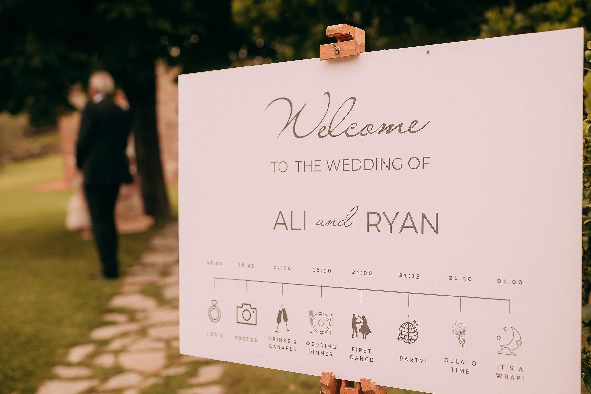 Elegant wedding welcome sign for Ali and Ryan, beautifully displayed with a detailed timeline of events.”