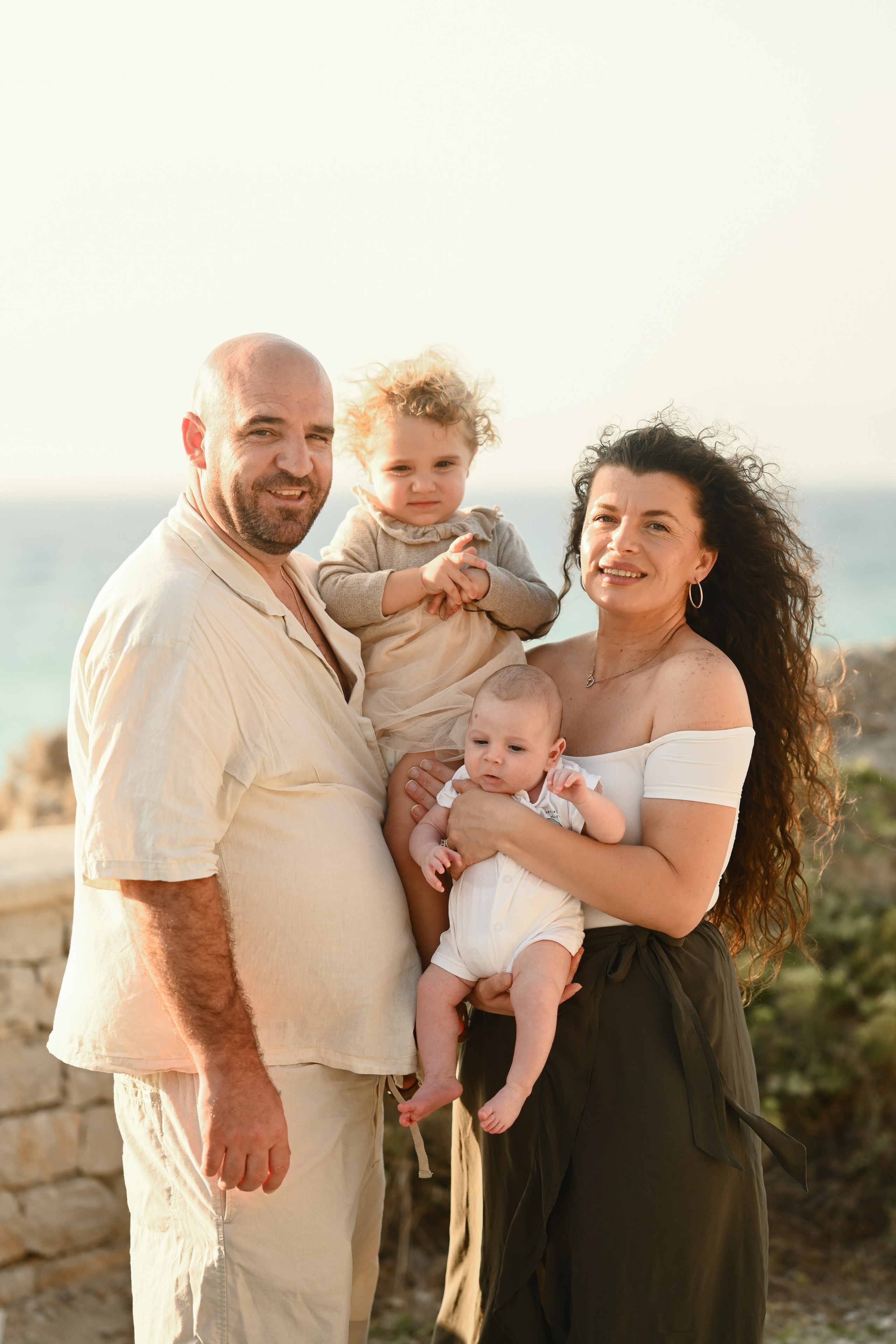 Happy family walking along a Rhodes beach at sunset. Photographer in Rhodes Island