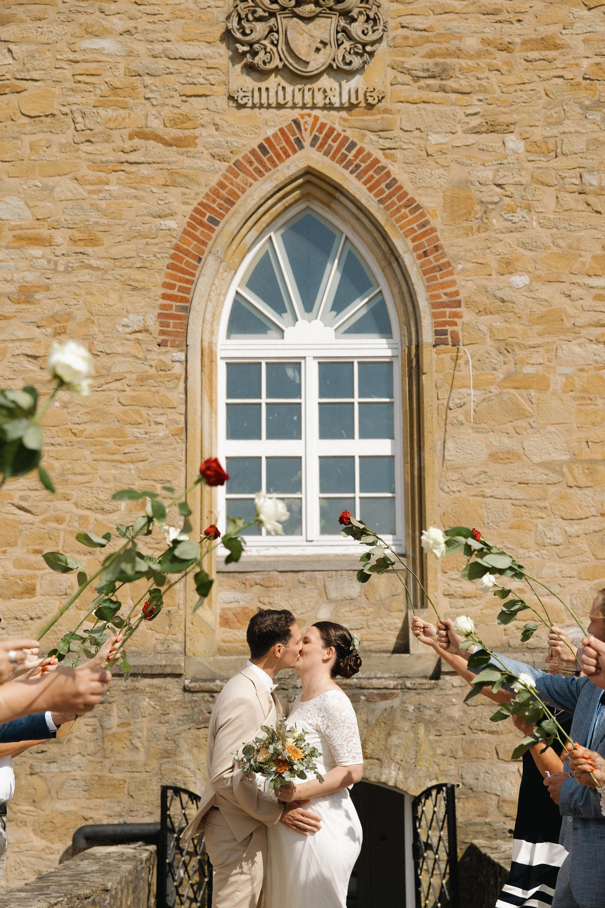 Romantischer Kuss des Brautpaares vor dem geschmückten Bogenfenster der Diedrichsburg, heiraten auf der Diedrichsburg