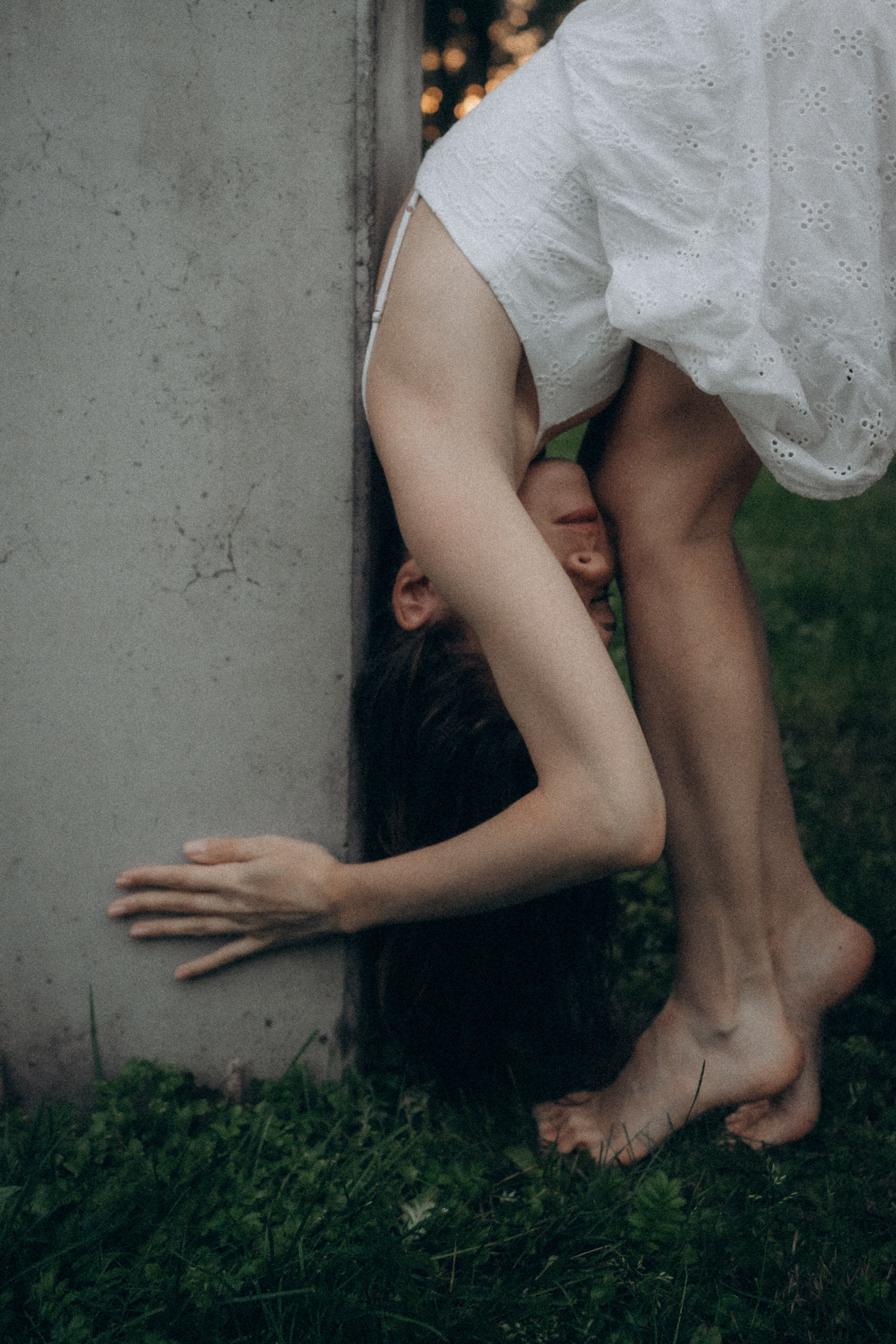 Fine art detail of a woman’s legs and hands against a concrete wall, outdoor portrait