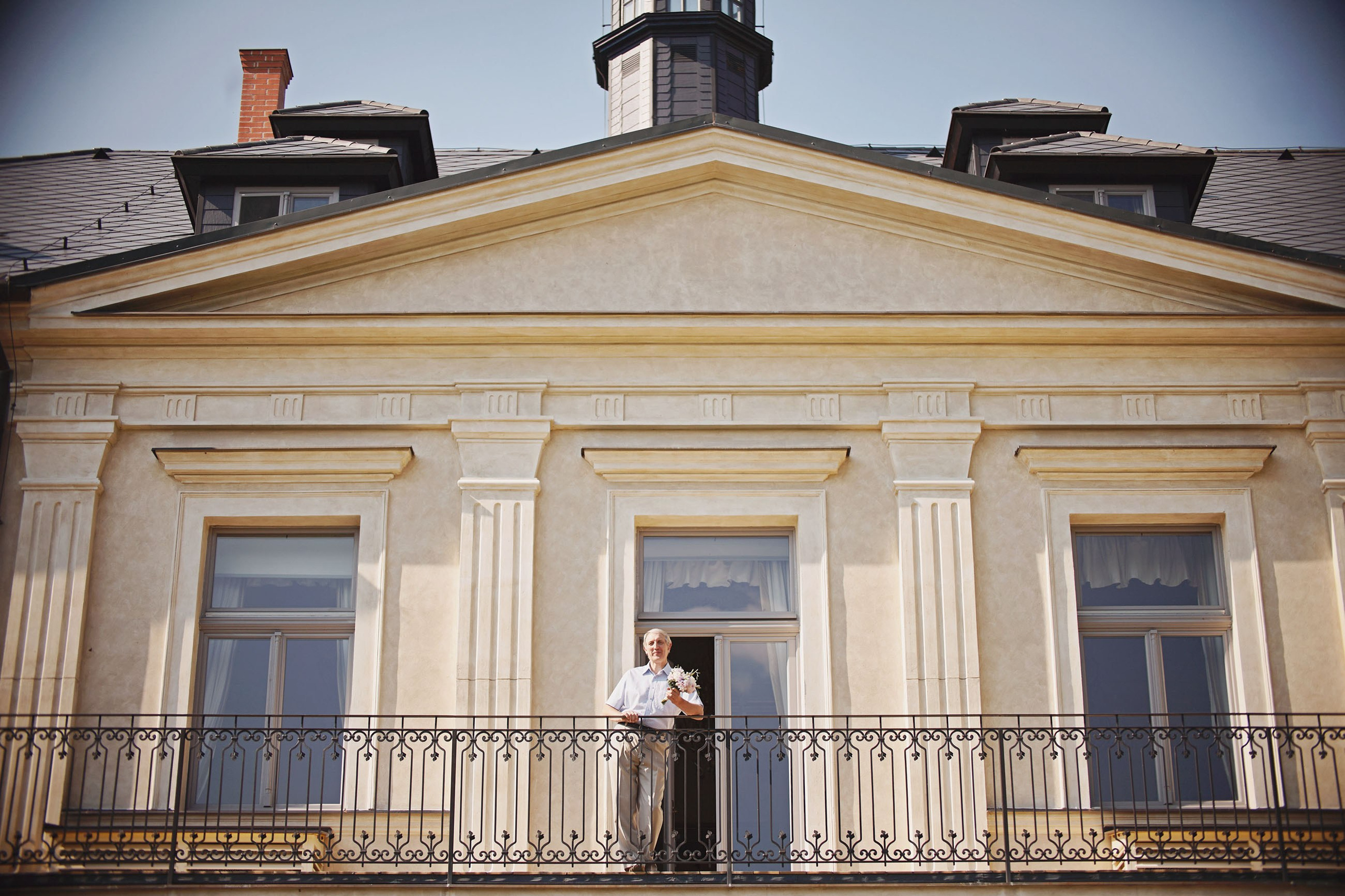 Father of the bride with bouquet on balcony at Chateau Mcely.