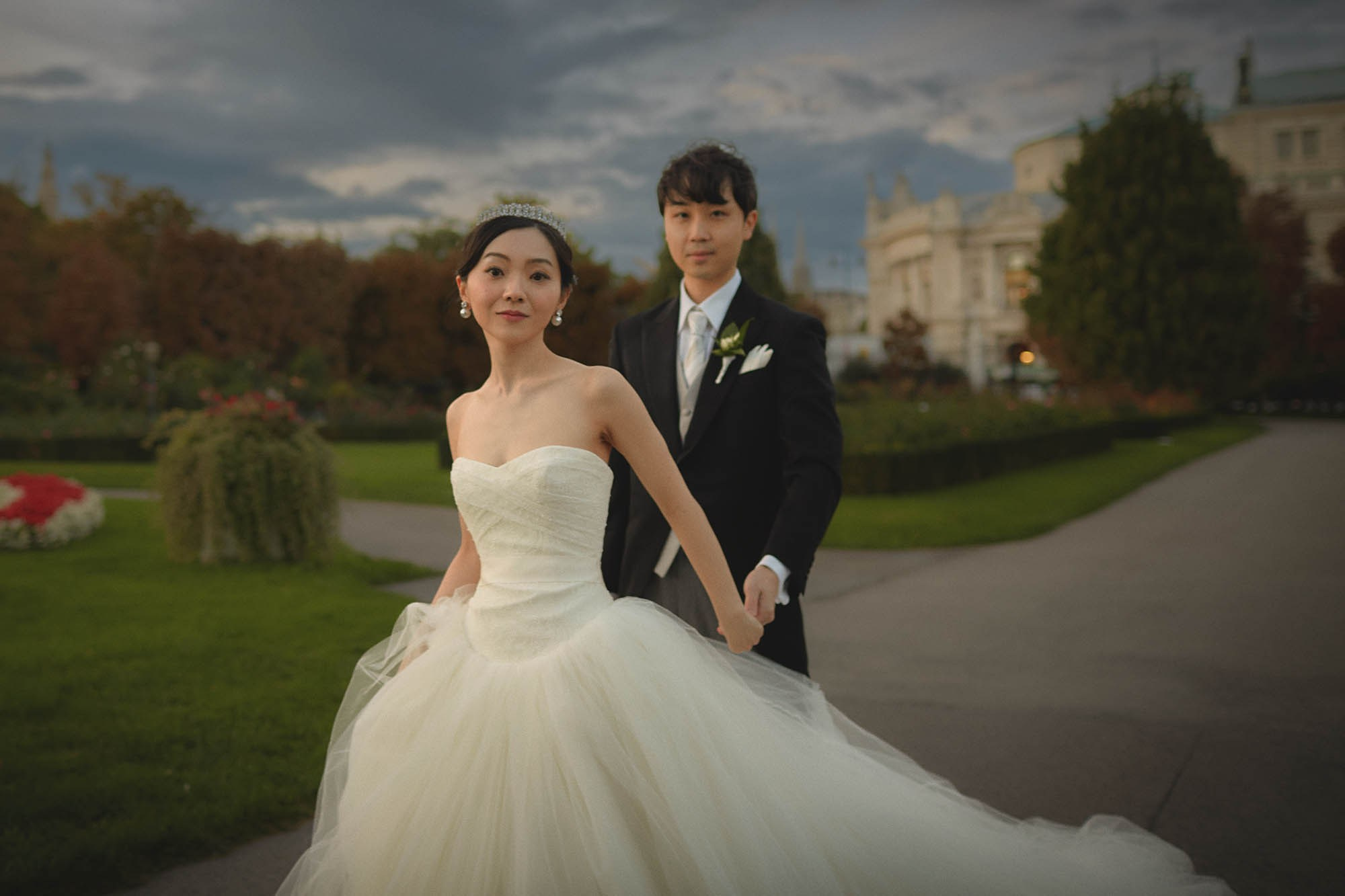 Newlyweds stopping for portrait in deserted Vienna garden.