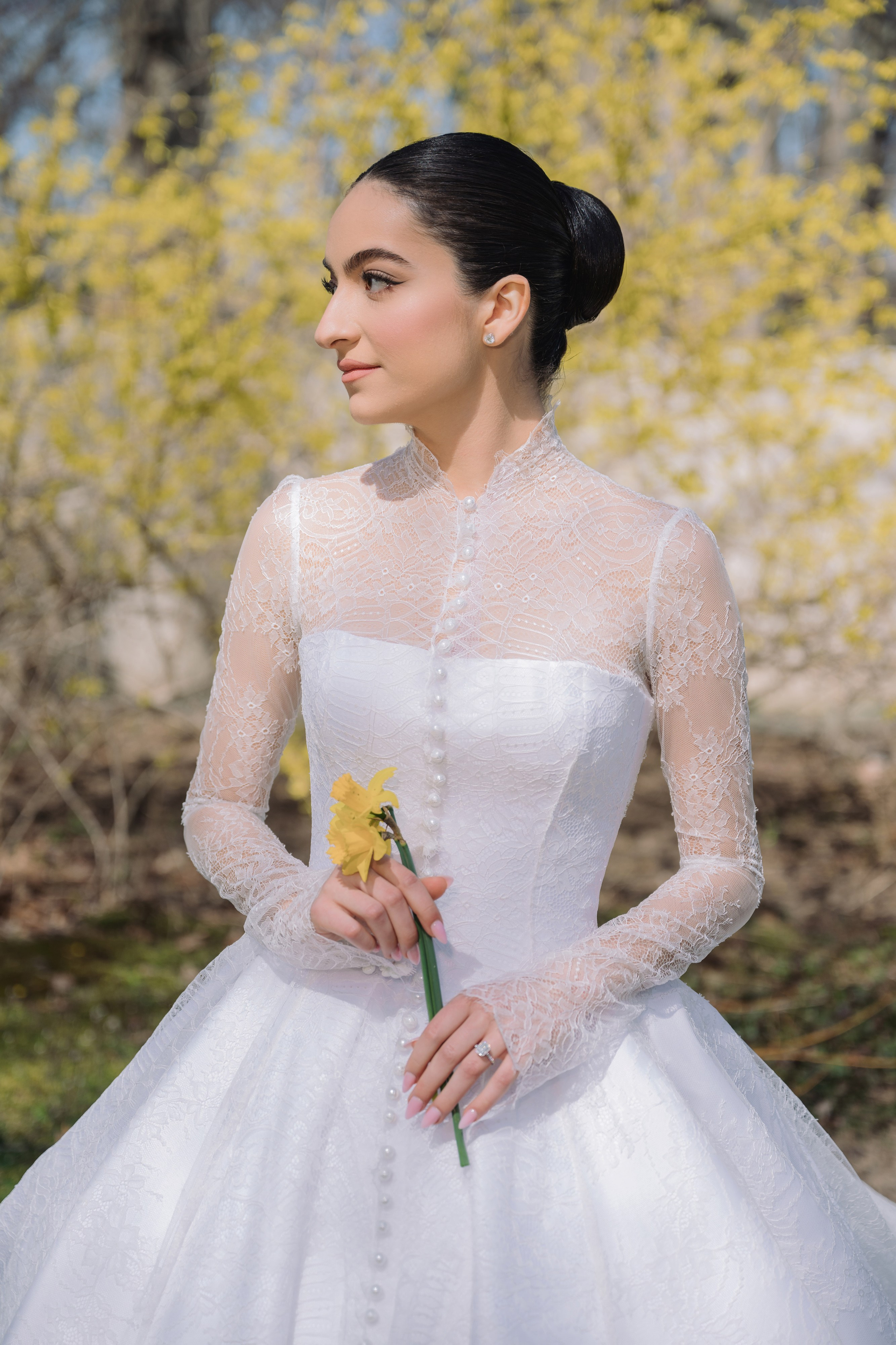 a woman in a white wedding dress holding a yellow flower