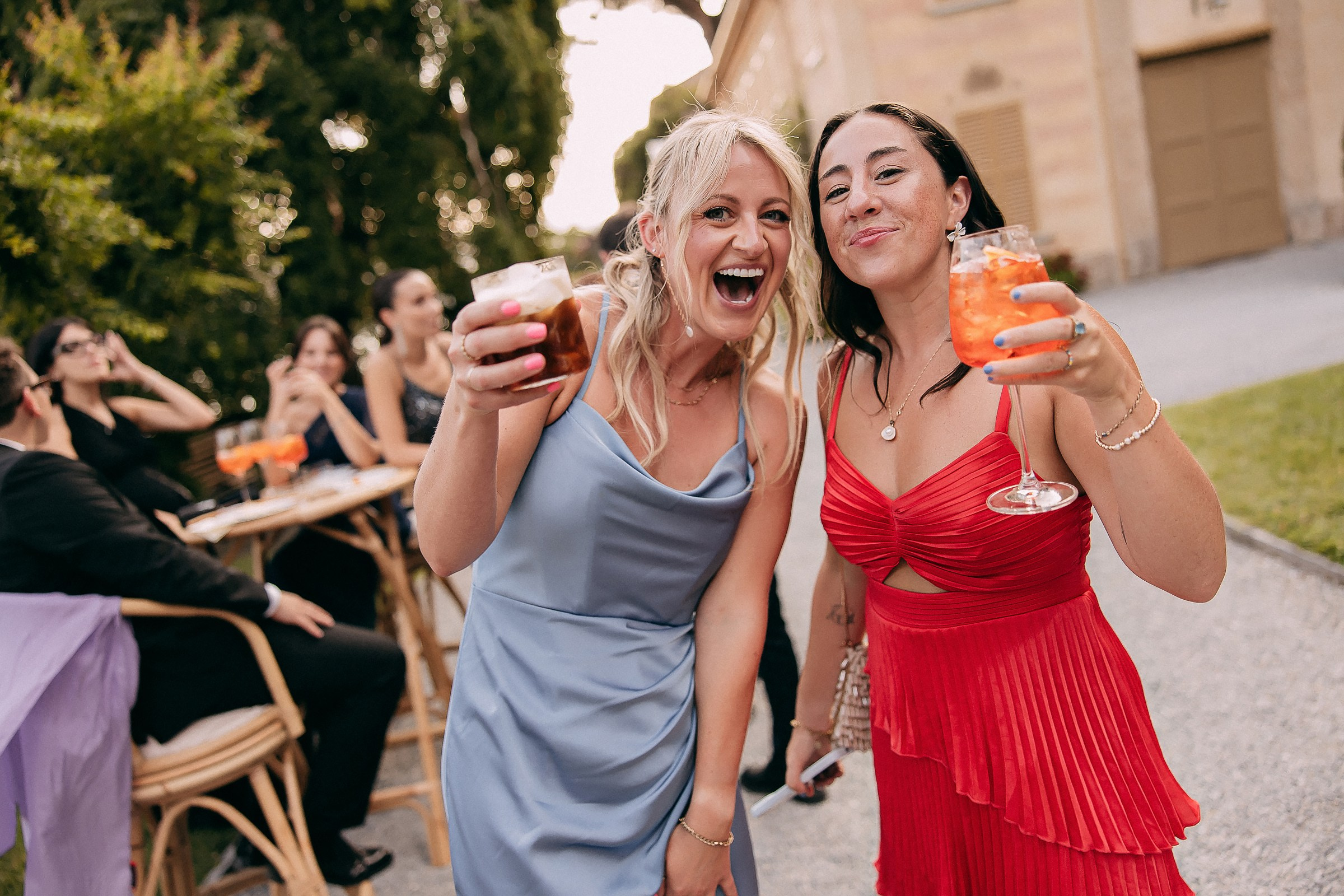 Two friends raise their drinks, smiling warmly at the camera during the festivities.