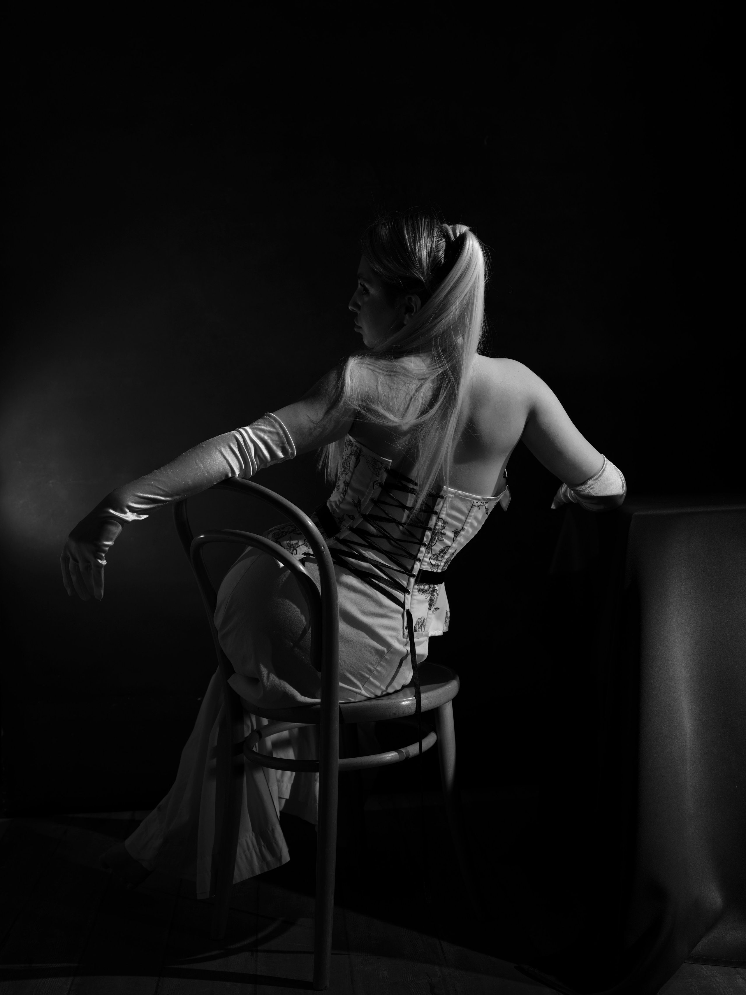 Cinematic black and white fashion portrait of a female model in a corset, emphasising the curve of the waist and sculptural body lines.
