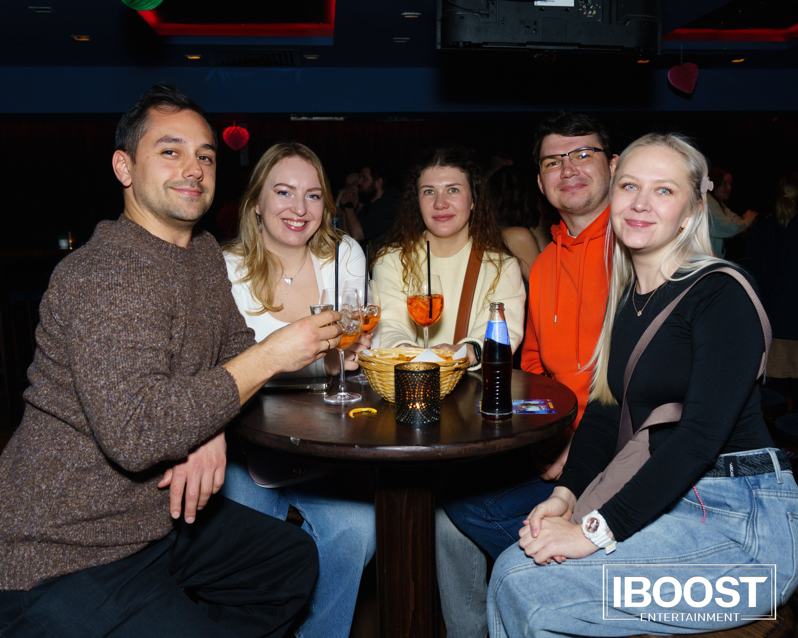 Five guests posing with drinks at a table during the Animal JazZ concert in Sofia.