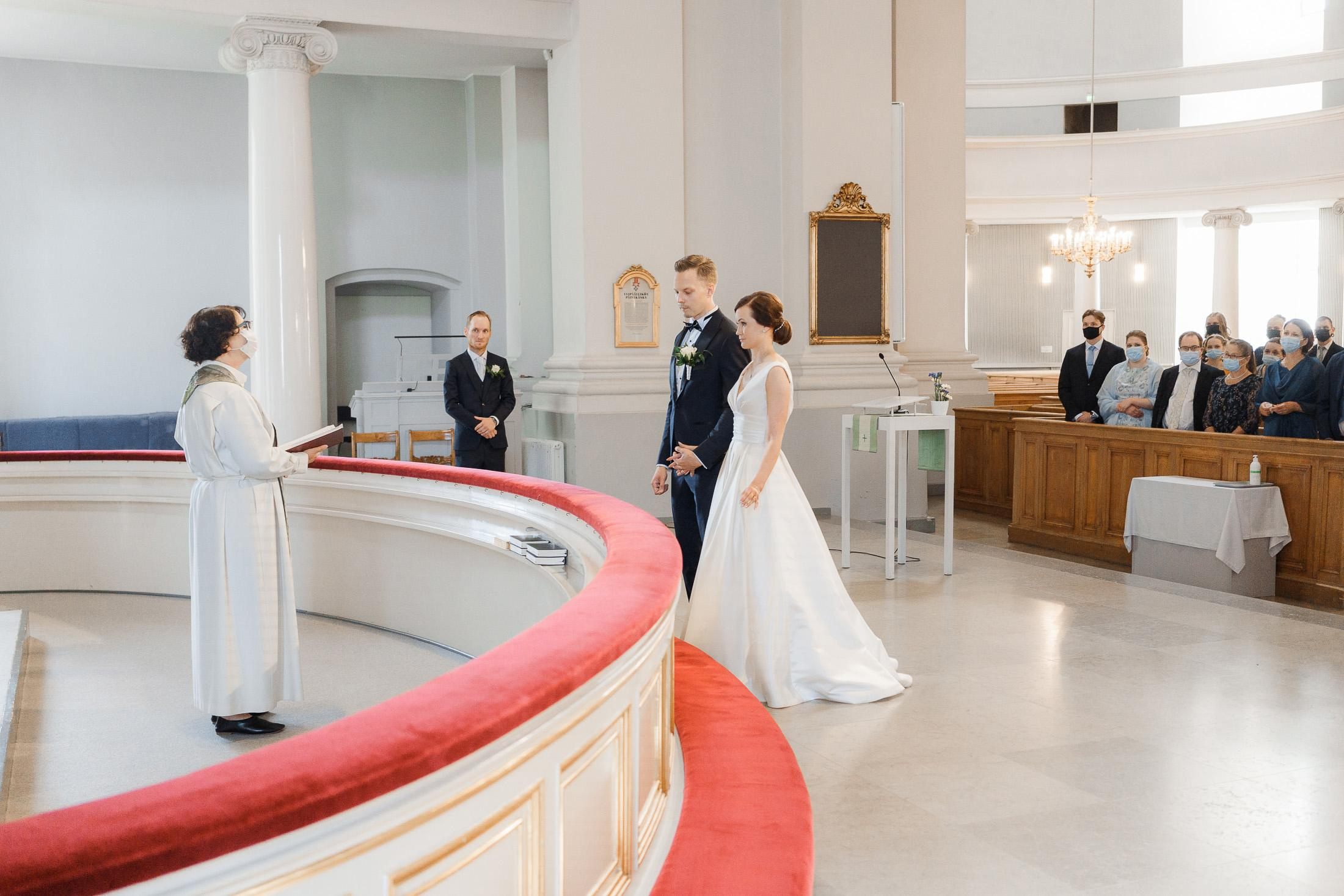 Morsian ja sulhanen seisovat alttarilla Helsingin Tuomion kirkossa