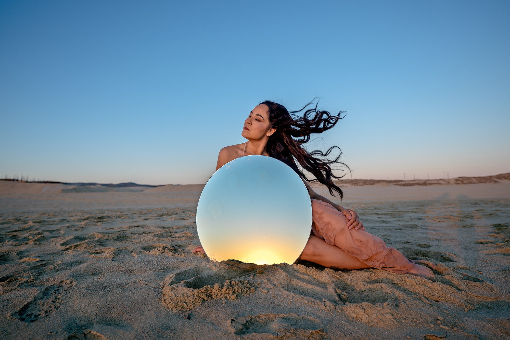 Woman sitting on Los Cabos beach holding a mirror during creative lifestyle portrait session