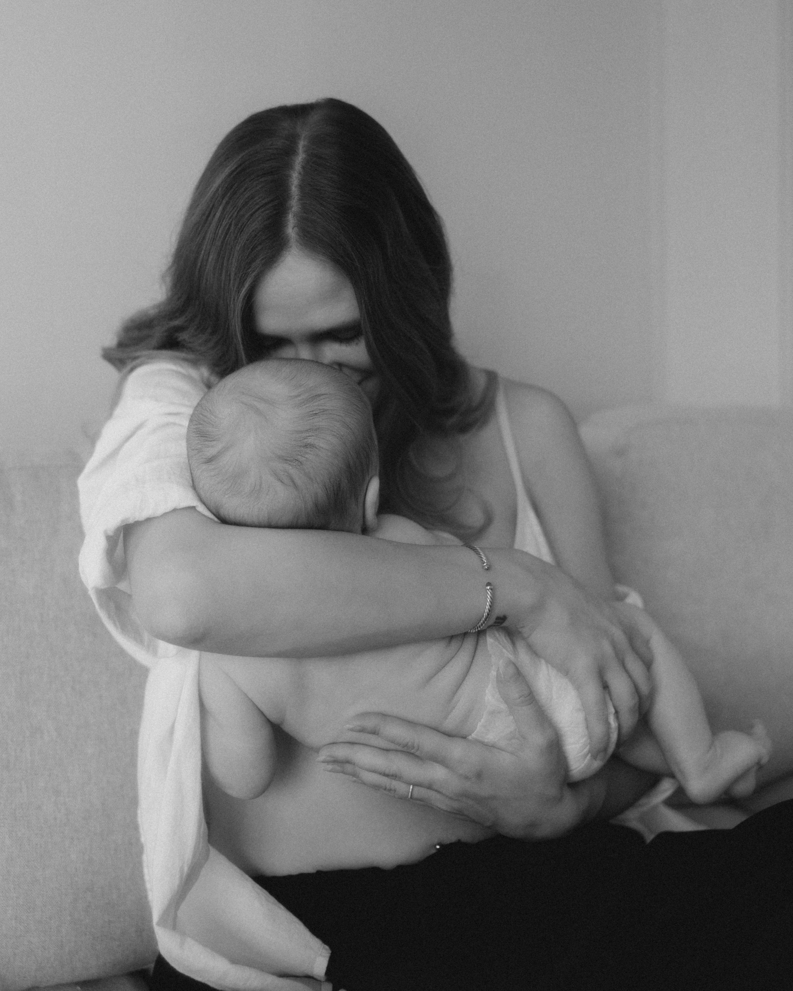 Mother cuddling her newborn wrapped in soft neutral tones, intimate lifestyle session