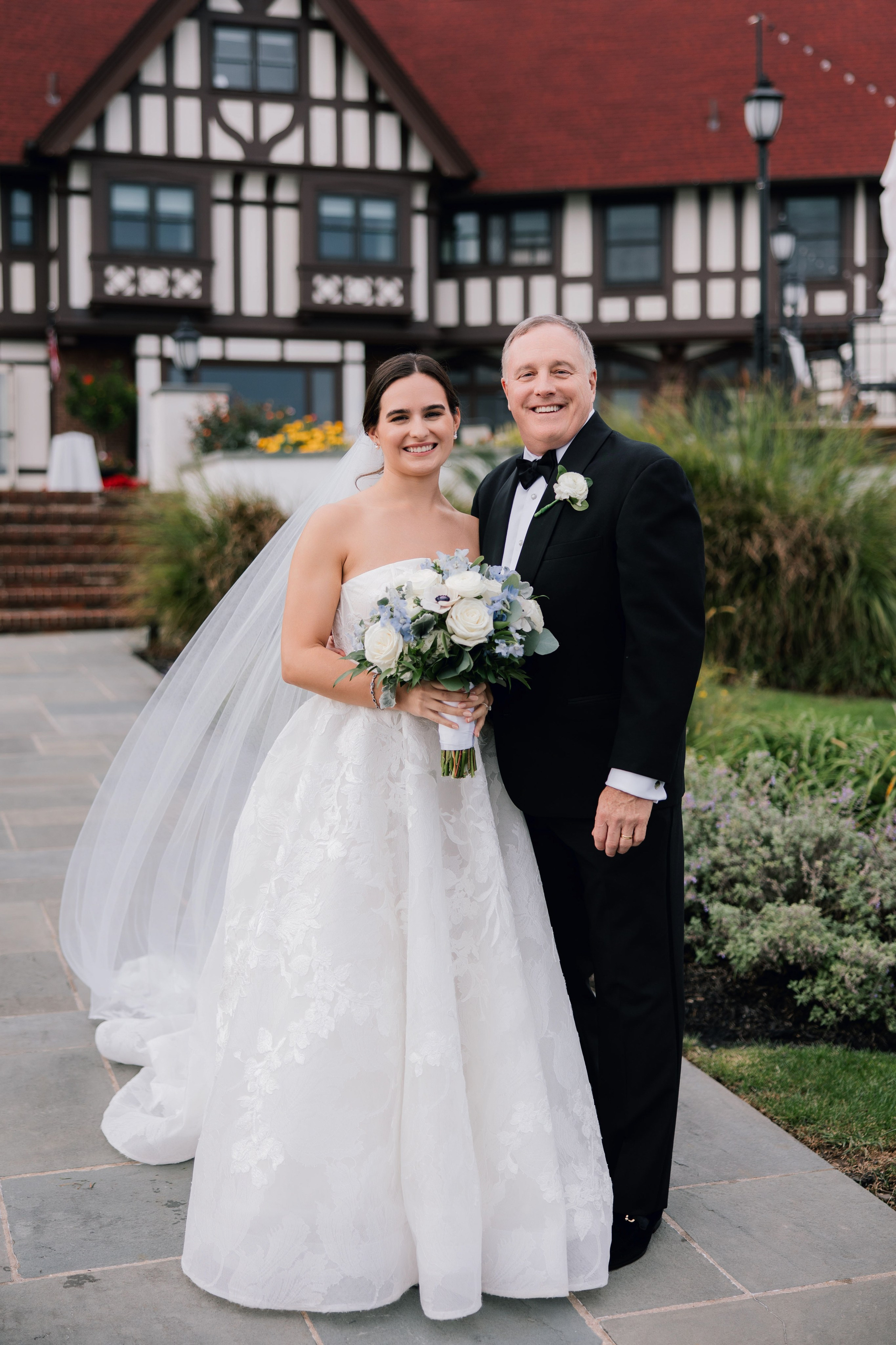 a bride and groom pose for a photo in front of a house