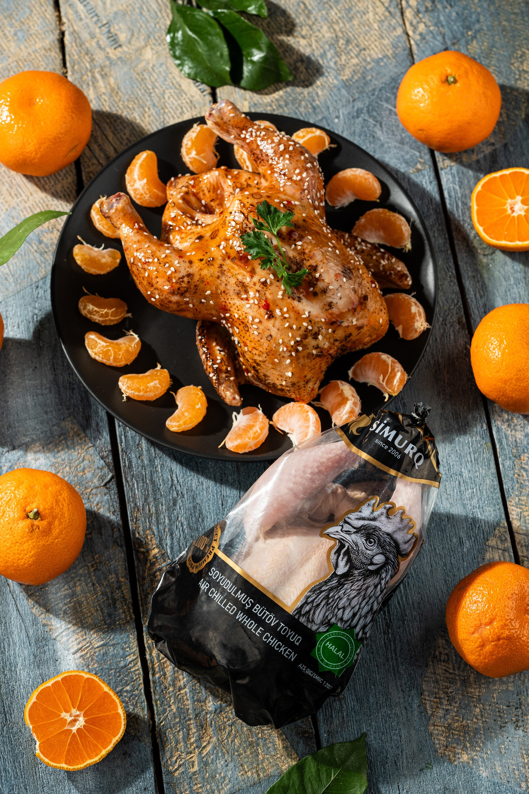 Simurq soyudulmuş bütün toyuq məhsulu – qablaşdırmada və bişmiş formada mandarin dilimləri ilə dekorlu vizual | halal məhsul fotoqrafiyası