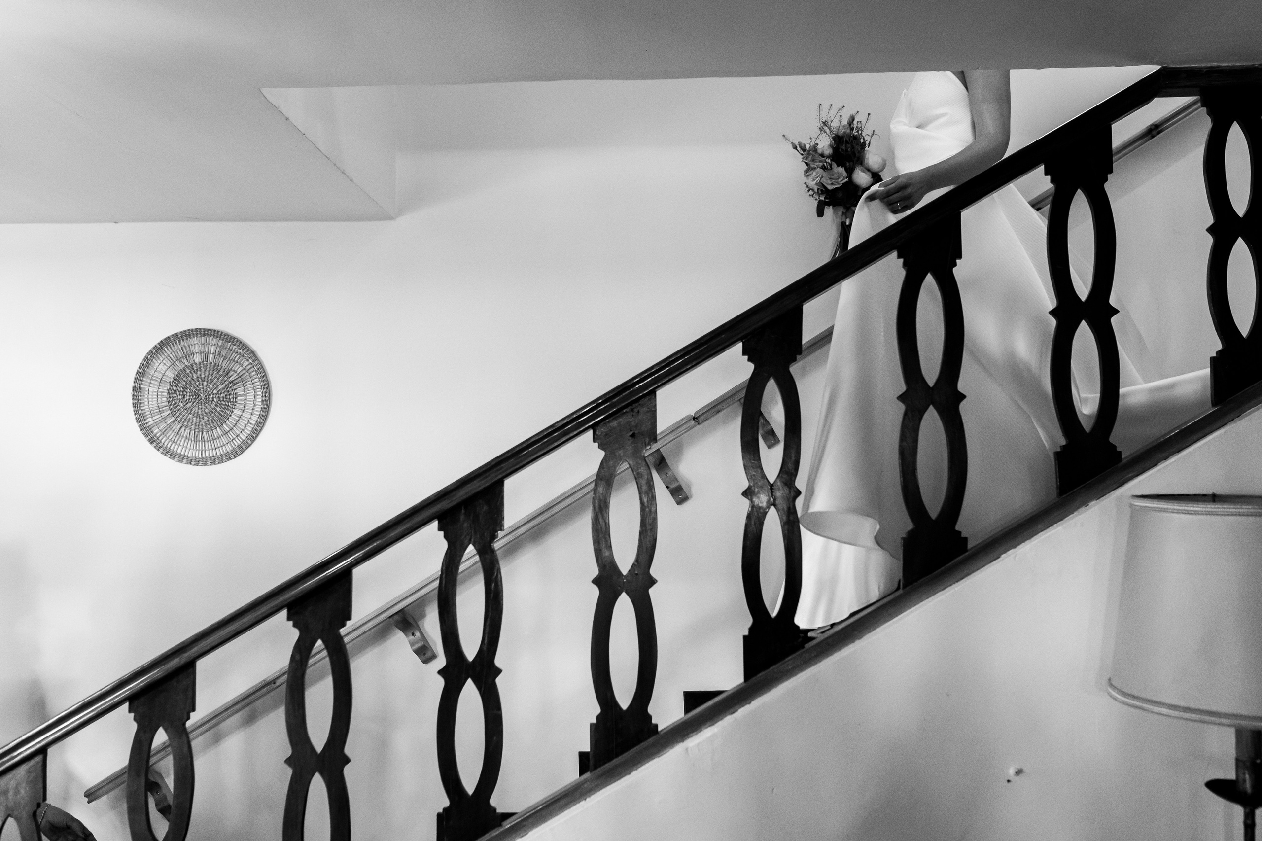Figura de la novia descendiendo escalera en blanco y negro, fotografía artística de boda