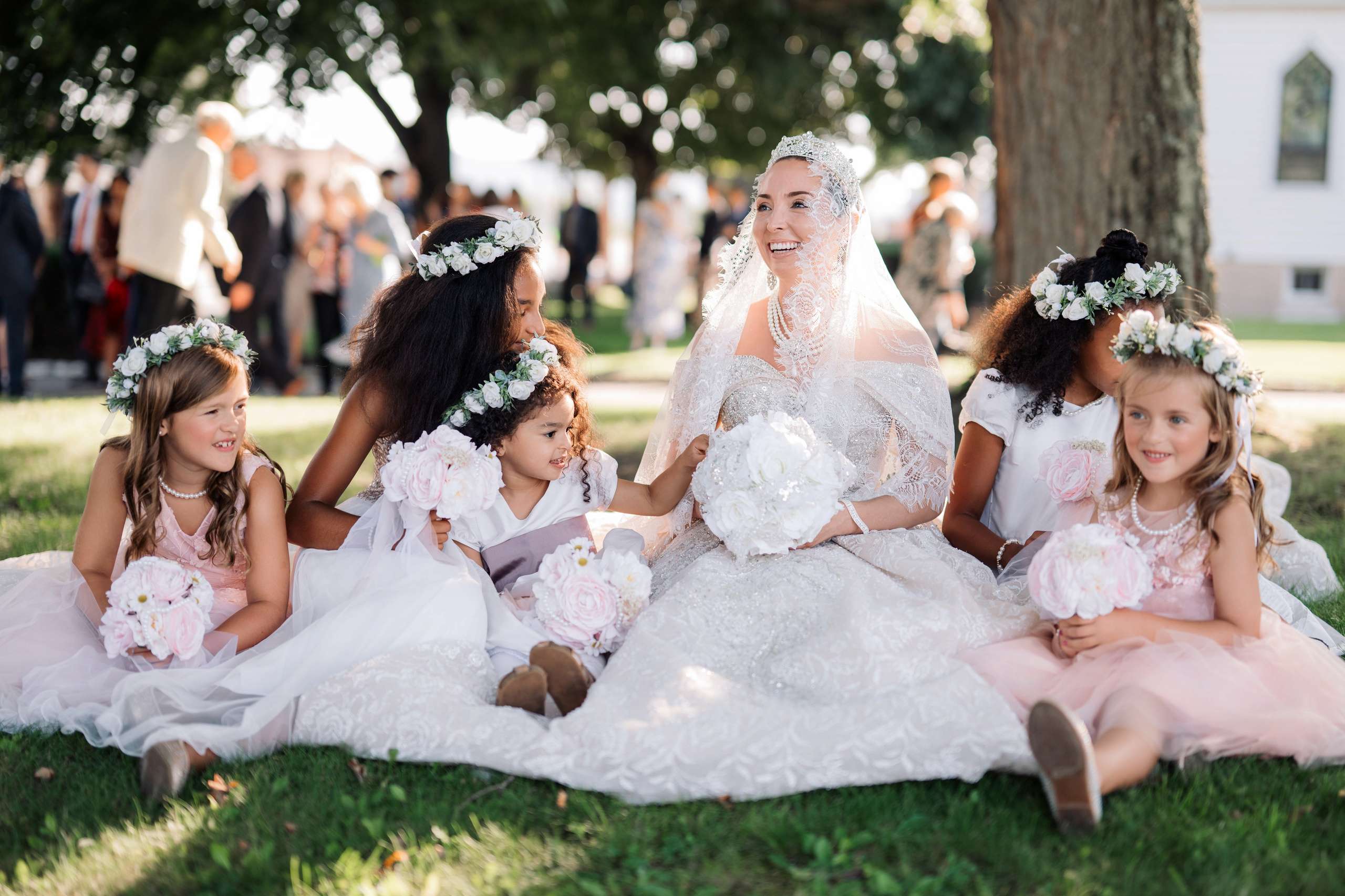 a bride and her bridesmaids sitting on the grass