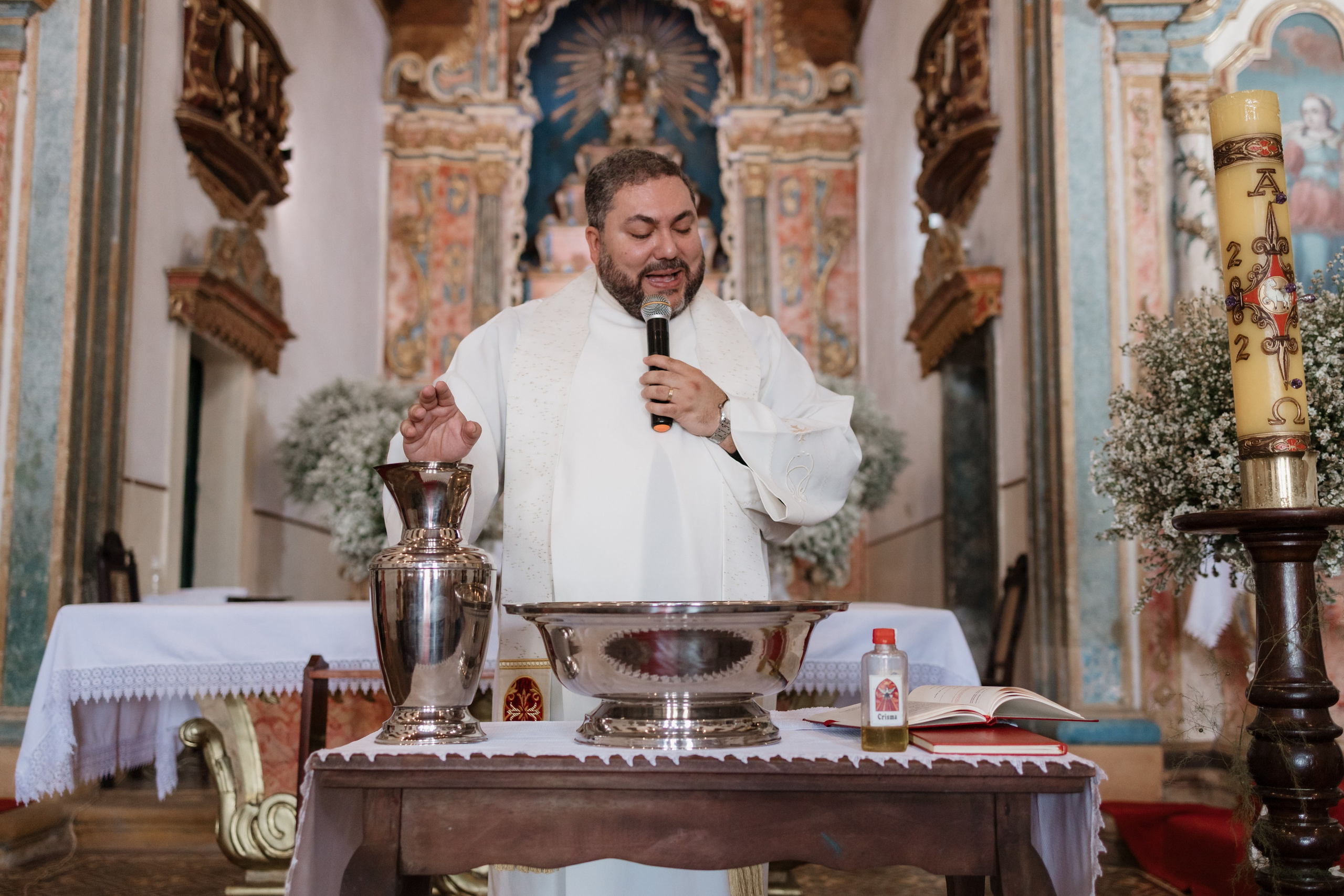 Detalhe do padre abençoando a água do batismo