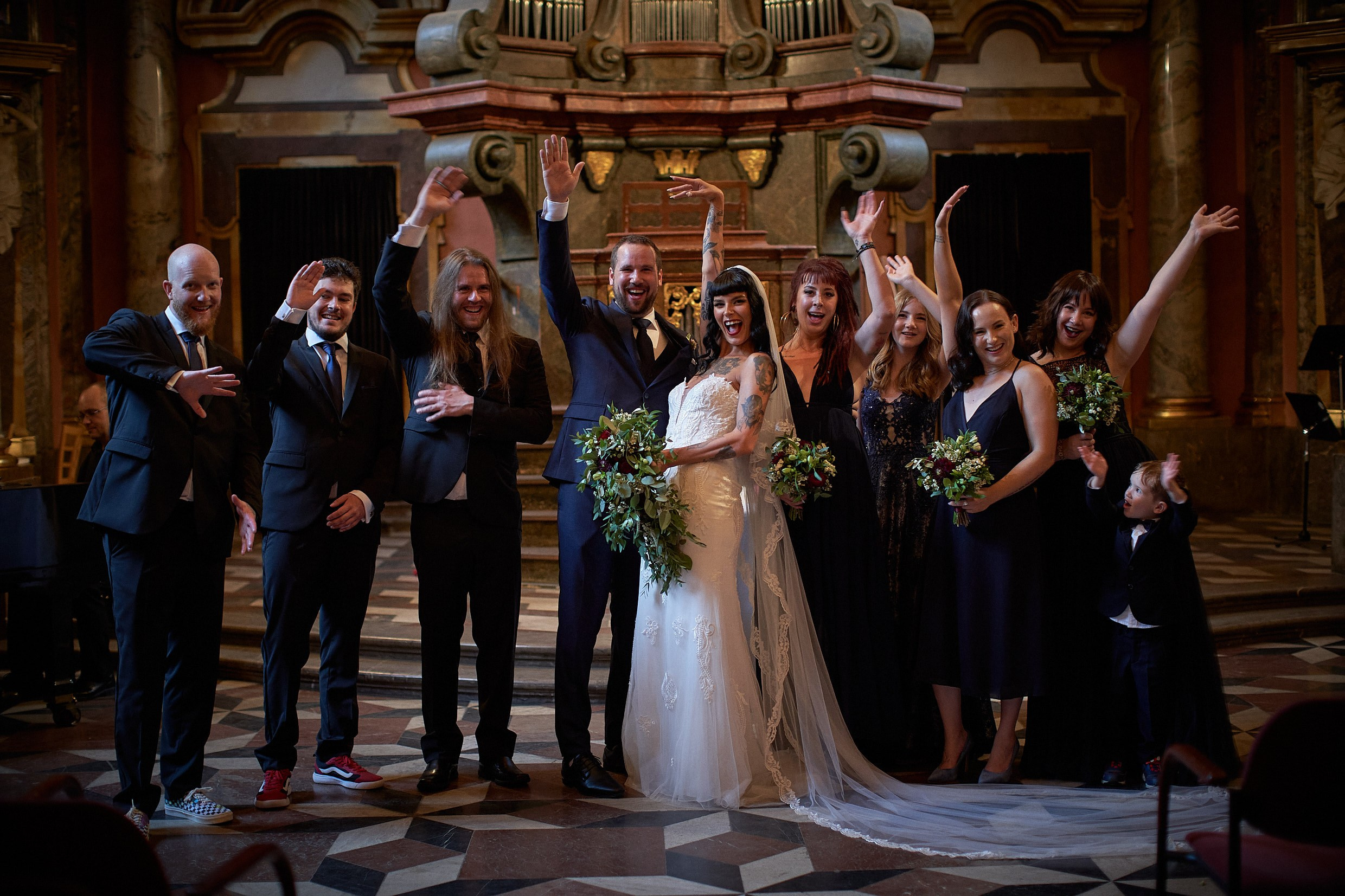 Happy newlyweds waving joyfully post-ceremony at altar.
