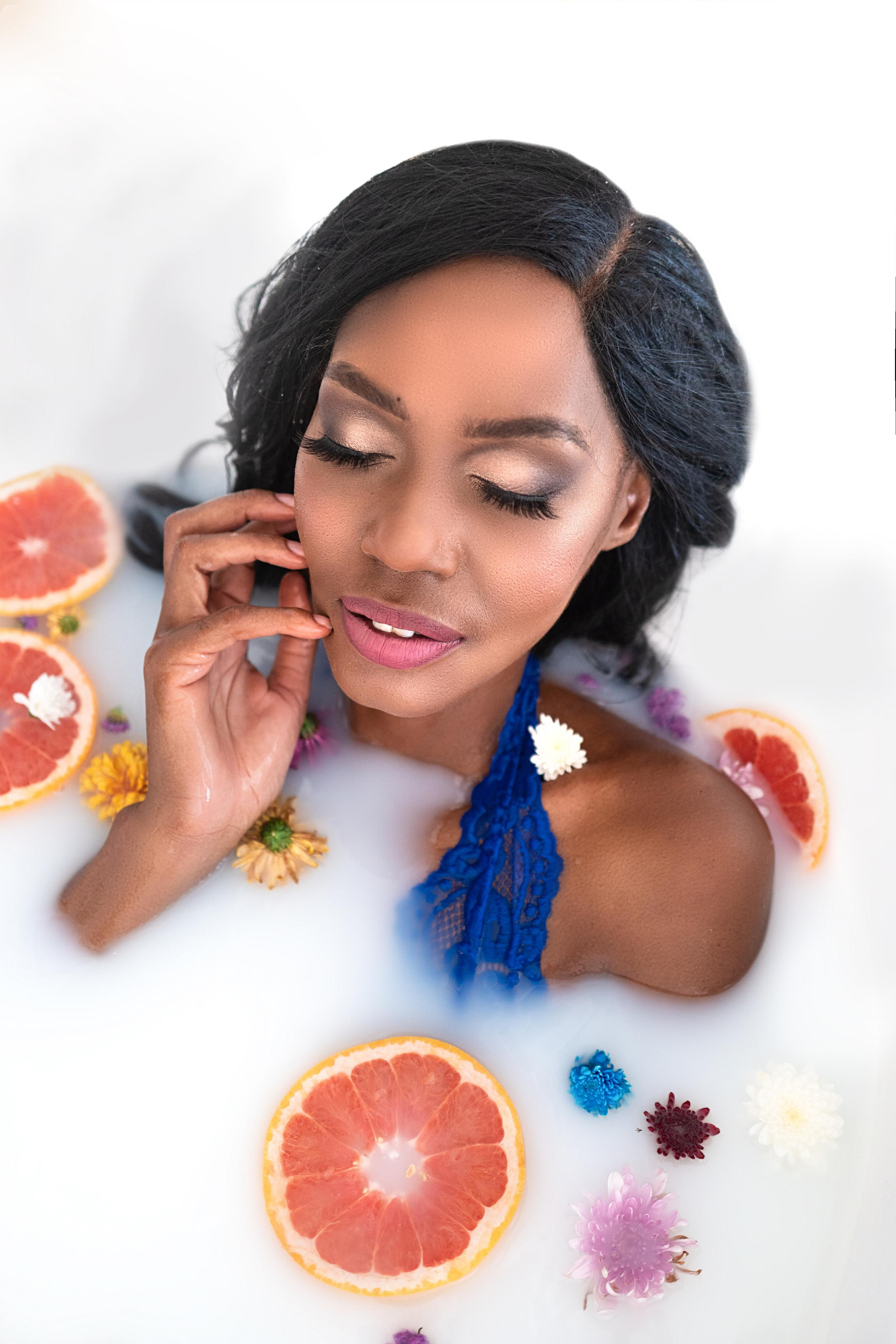 woman in a bath filled with milk, flowers, and fruits