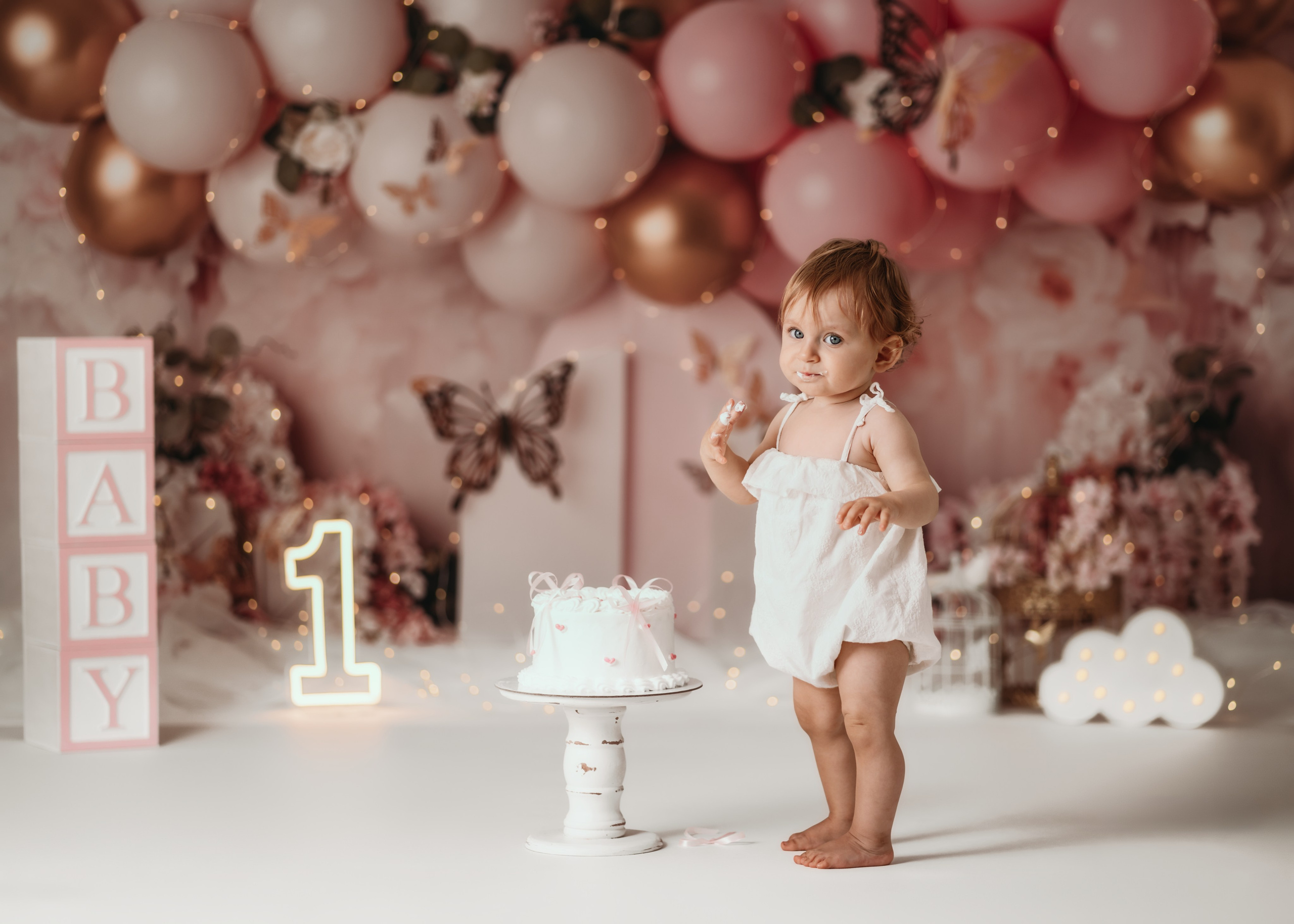 Cake smash devojčica u roze haljinici u bajkovitoj scenografiji leptira