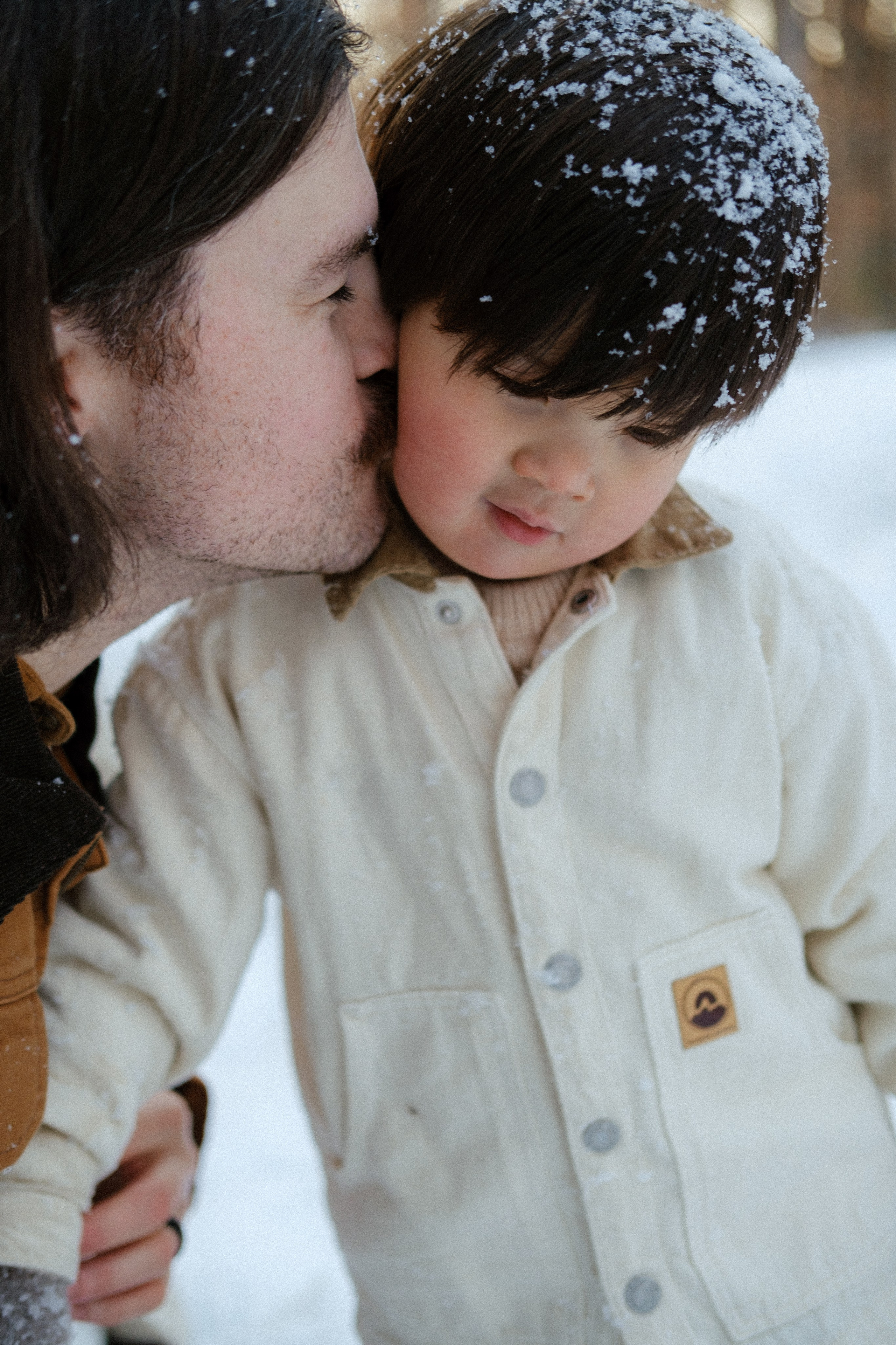 Dad kissing his baby boy after playing with snow, boy is all covered in snow in Richmond, VA