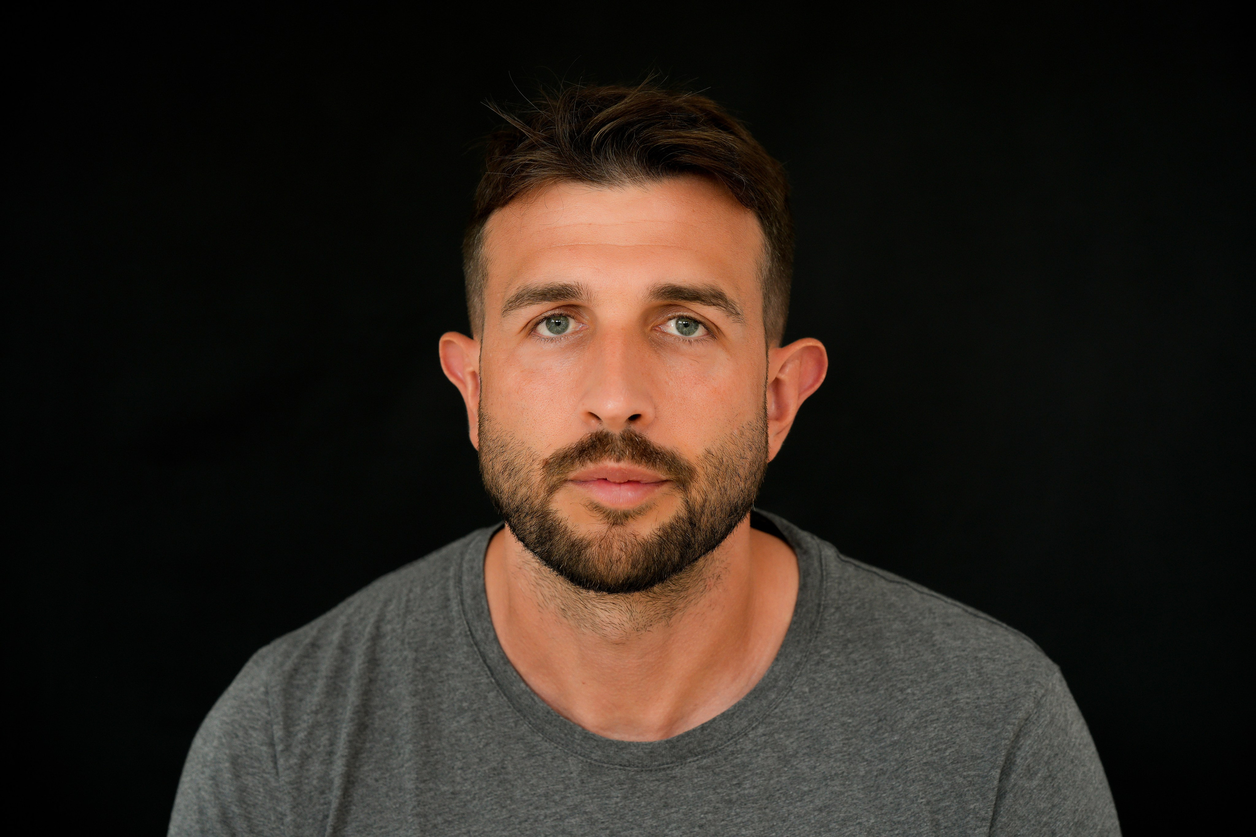 Professional headshot in Solihull of a young male in a grey shirt, natural light highlighting his face