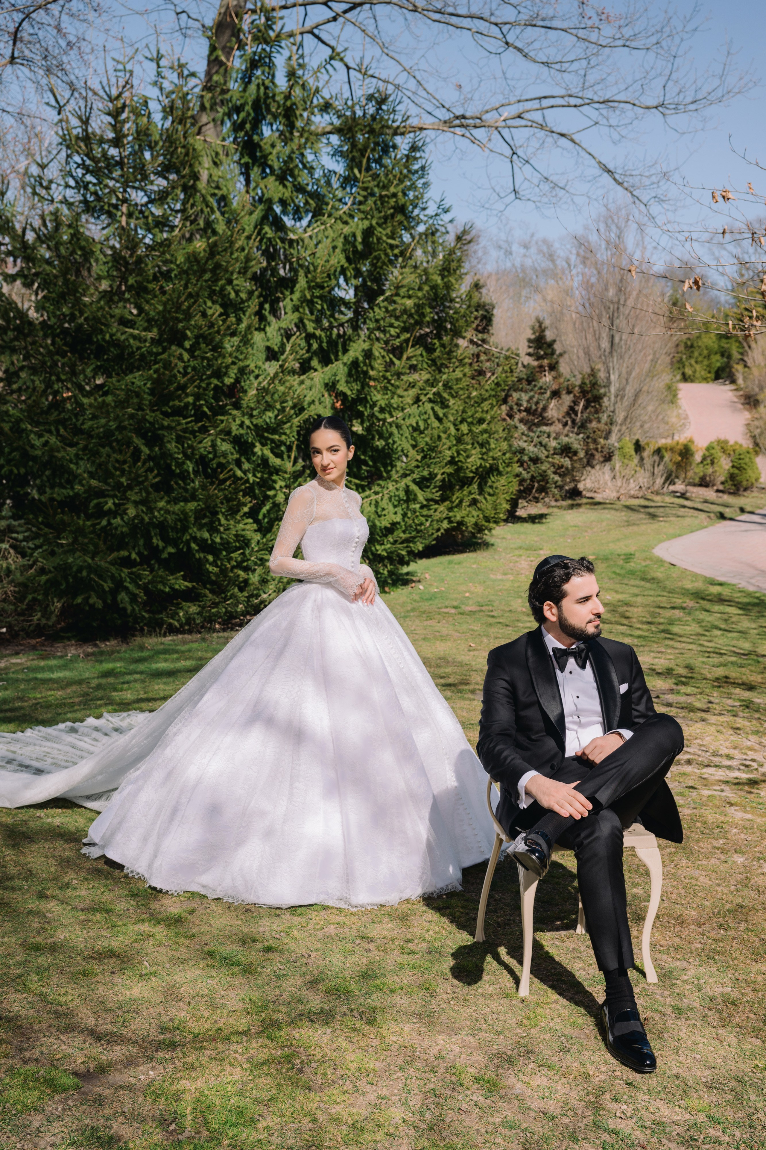 a bride and groom sitting on a chair in the grass