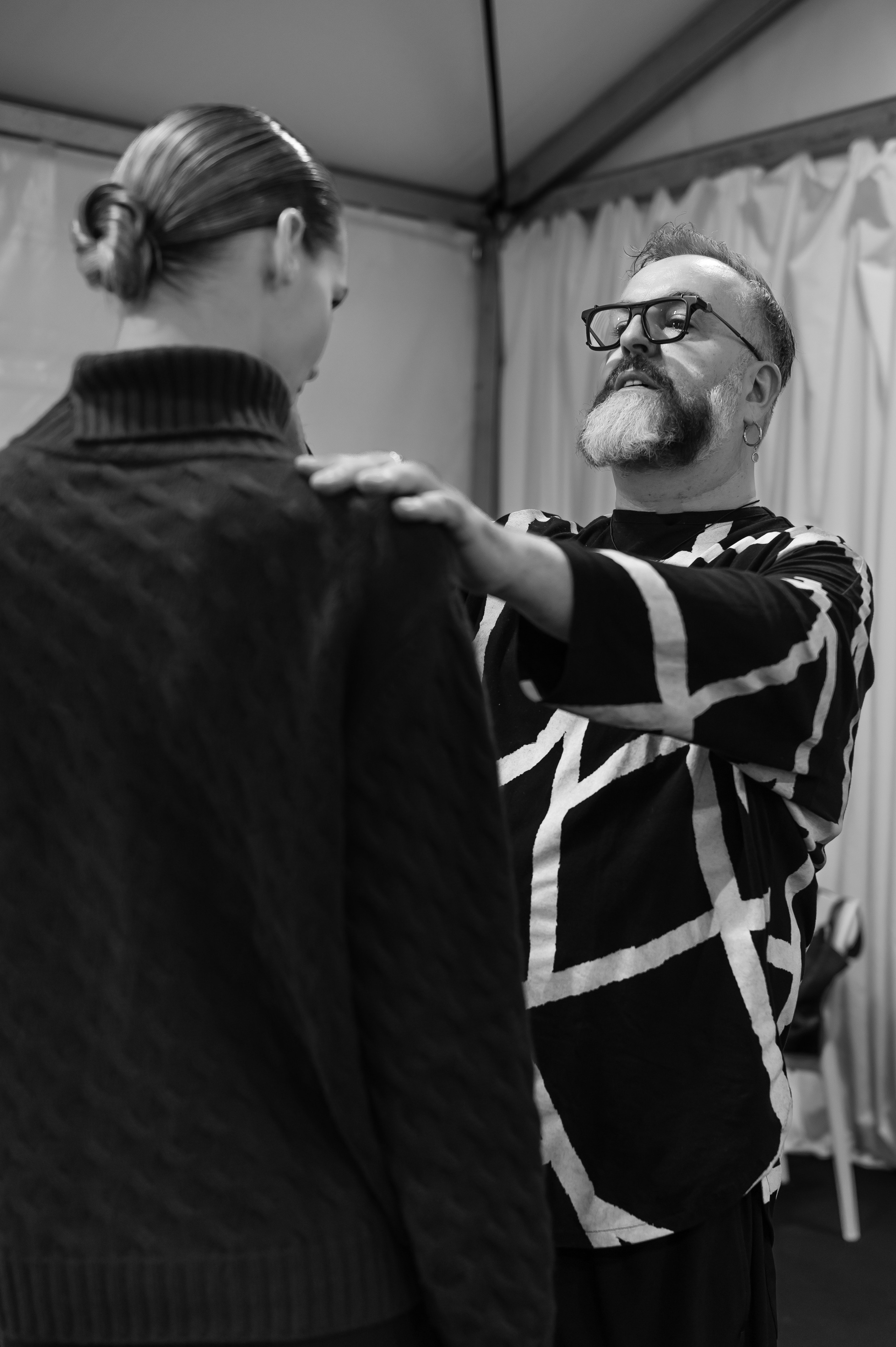 Fashion stylist adjusting outfit backstage before the runway