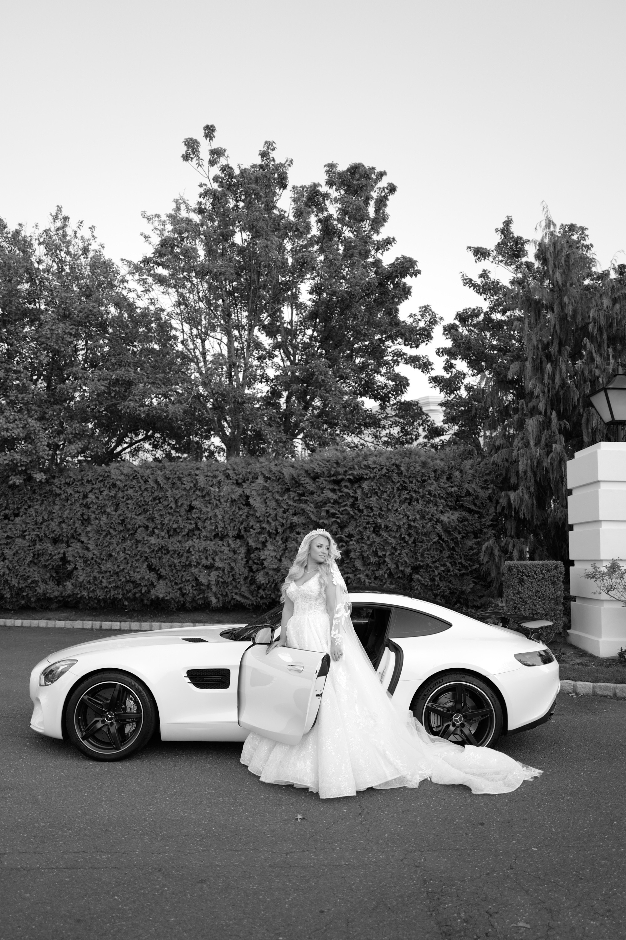a bride poses in front of a white sports car