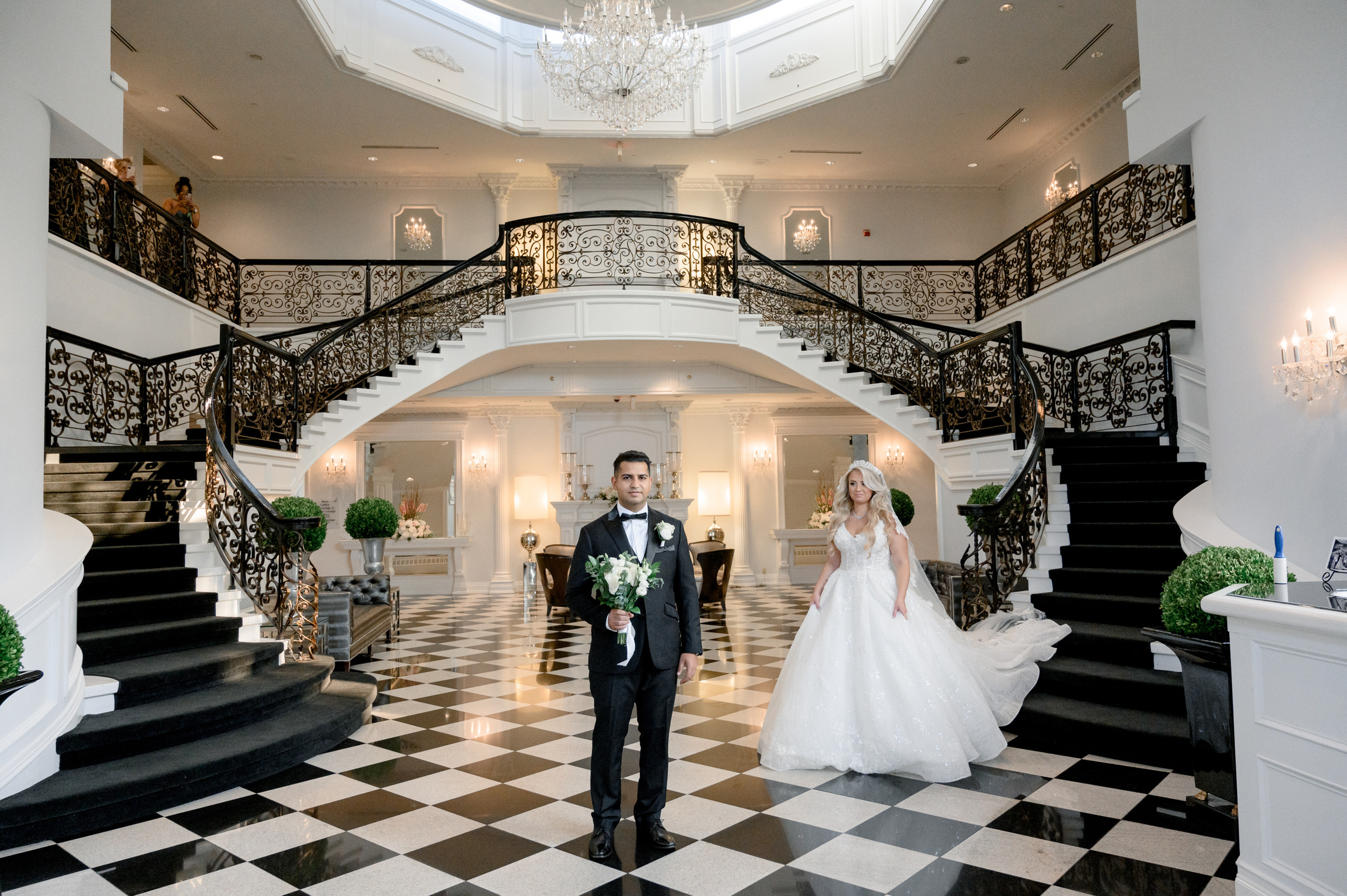 a bride and groom walking down the stairs of a mansion