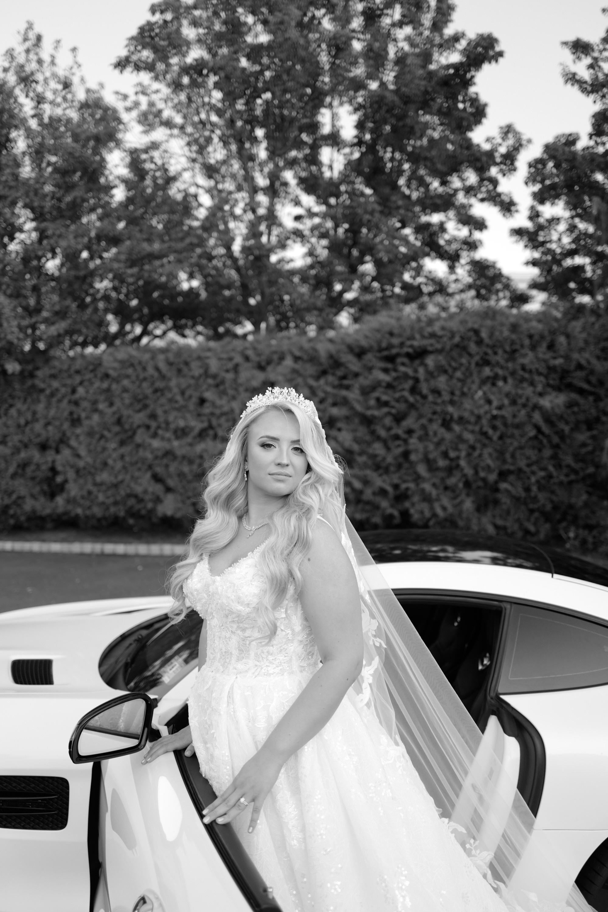 a bride standing next to her white car