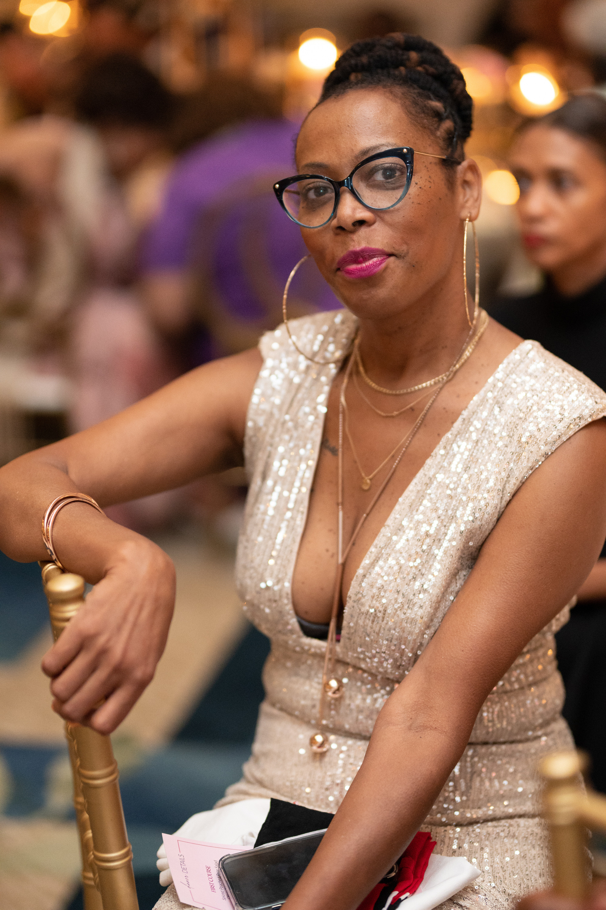 a woman in a dress and glasses sitting at a table