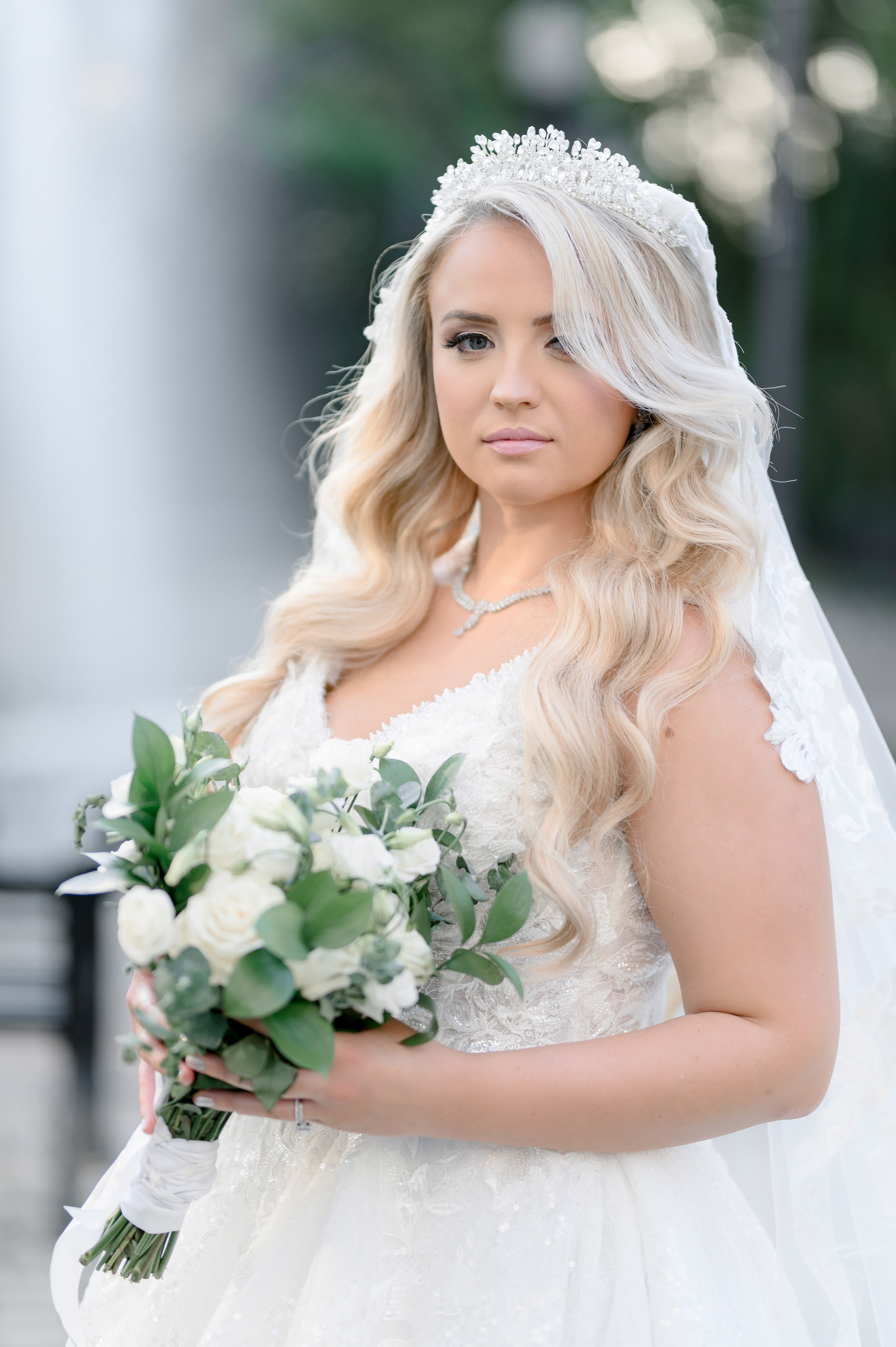 a bride holding her bouquet in front of a fountain