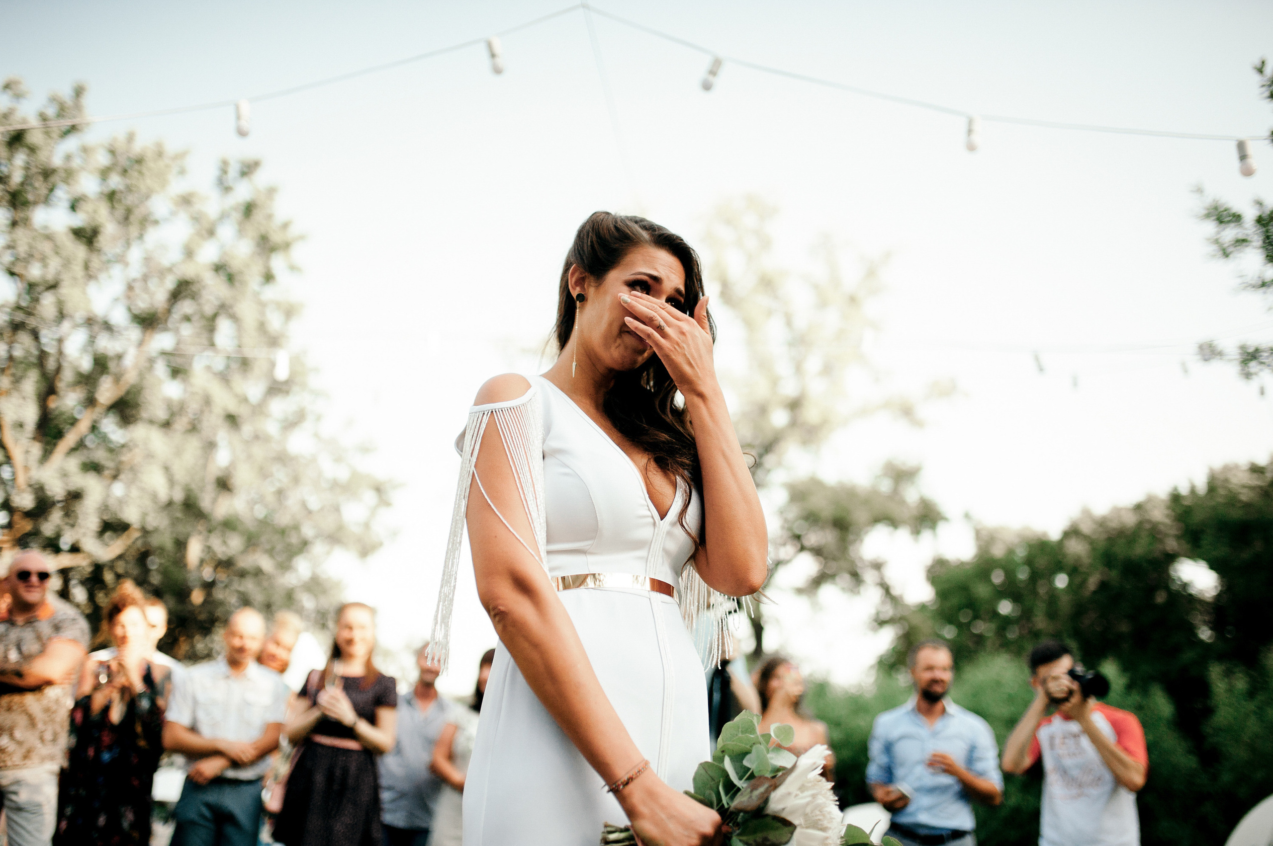 a woman in a white dress is talking on a cell