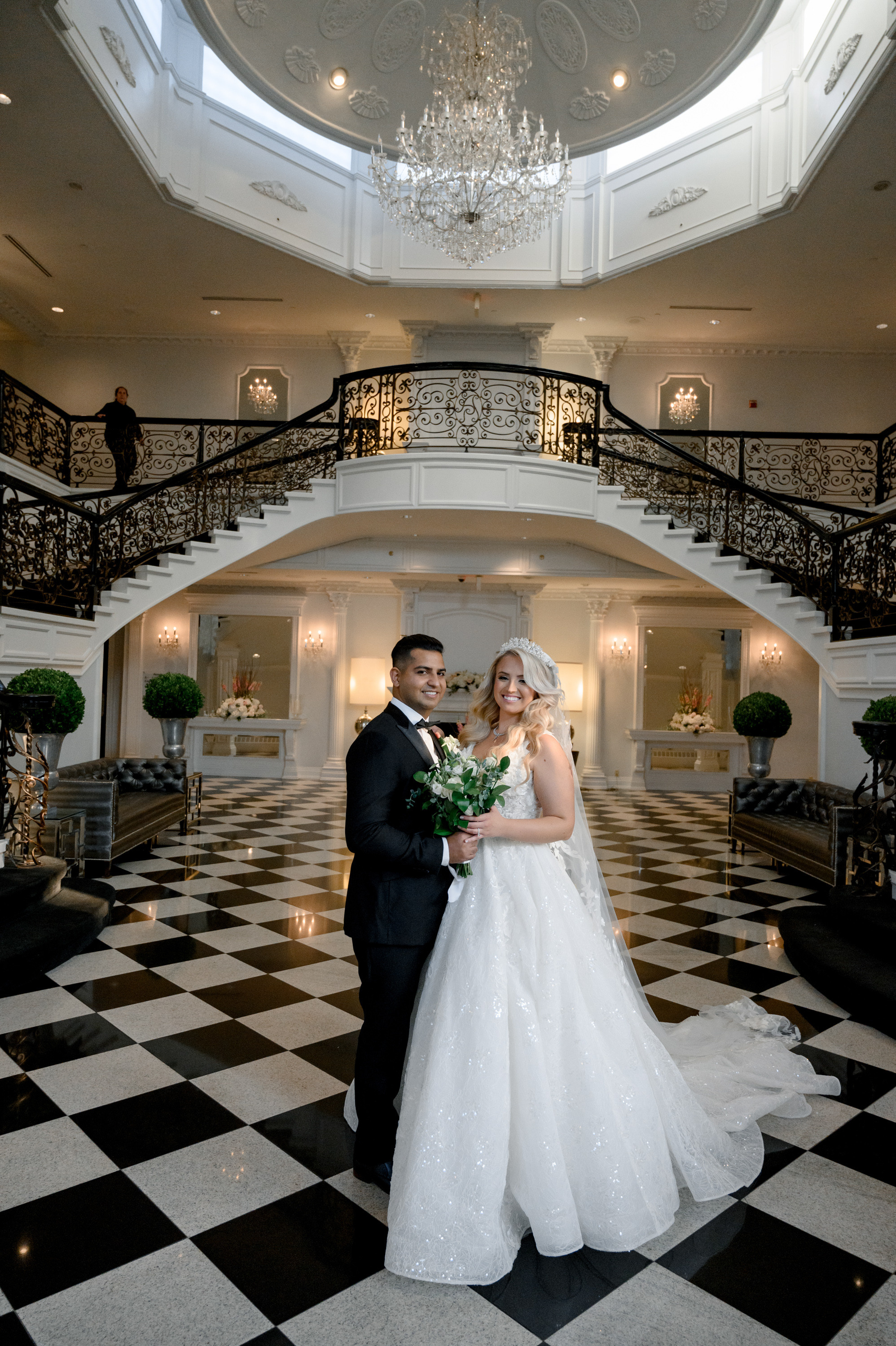 a bride and groom pose for a photo in a grand ballroom
