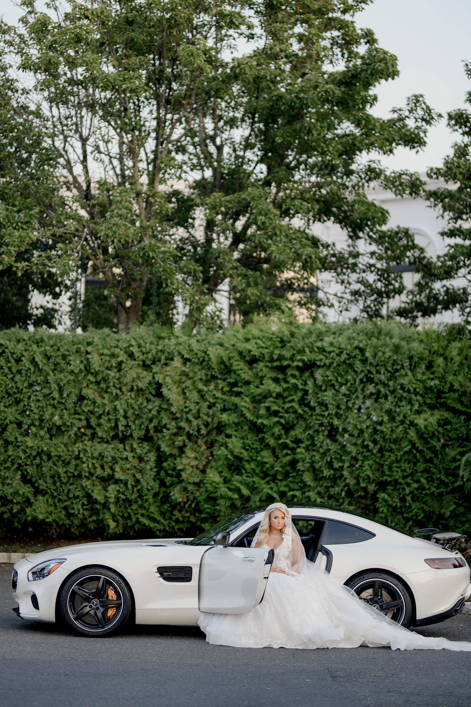 a bride in a white dress standing next to a white sports car