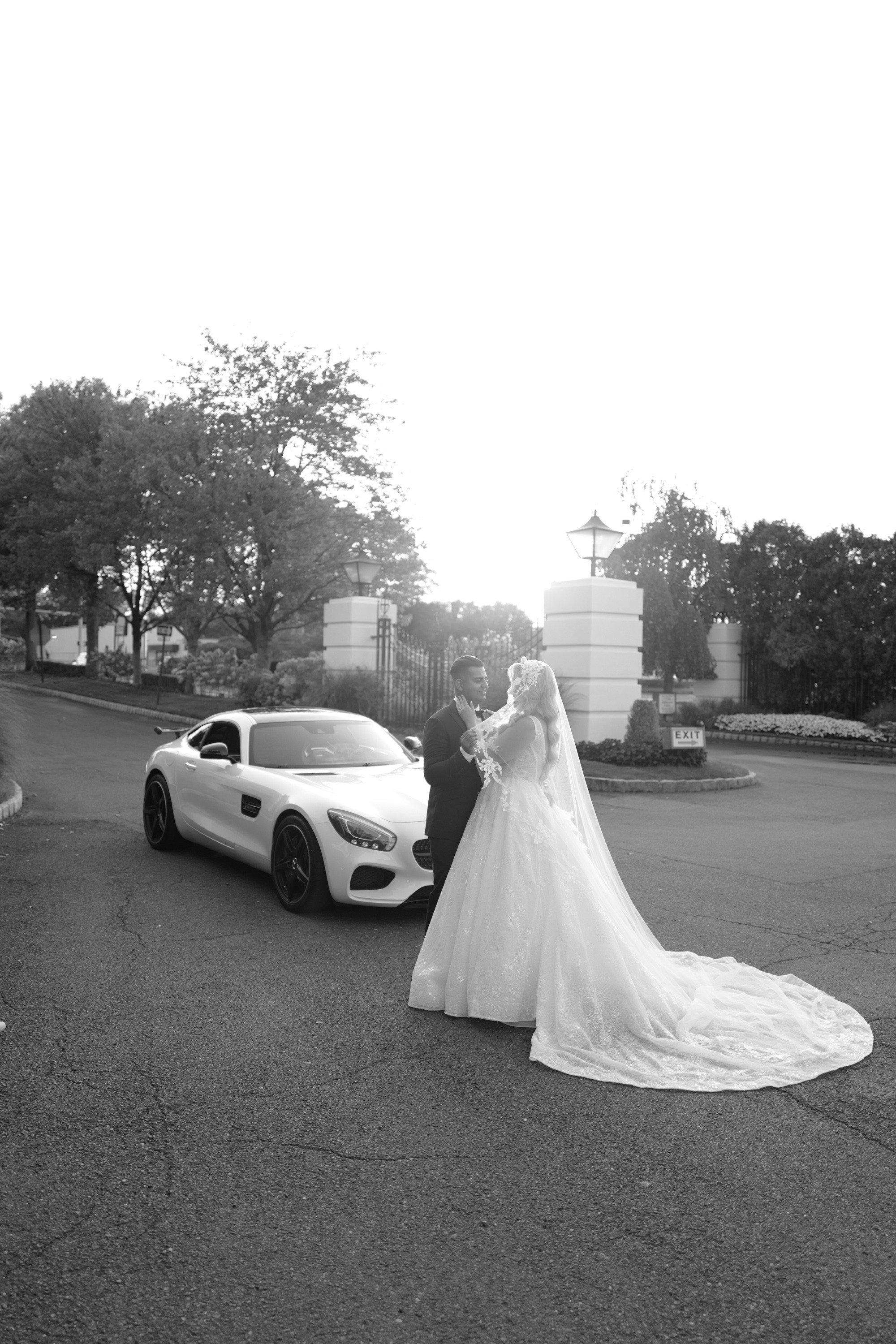 a bride and groom standing in front of a car