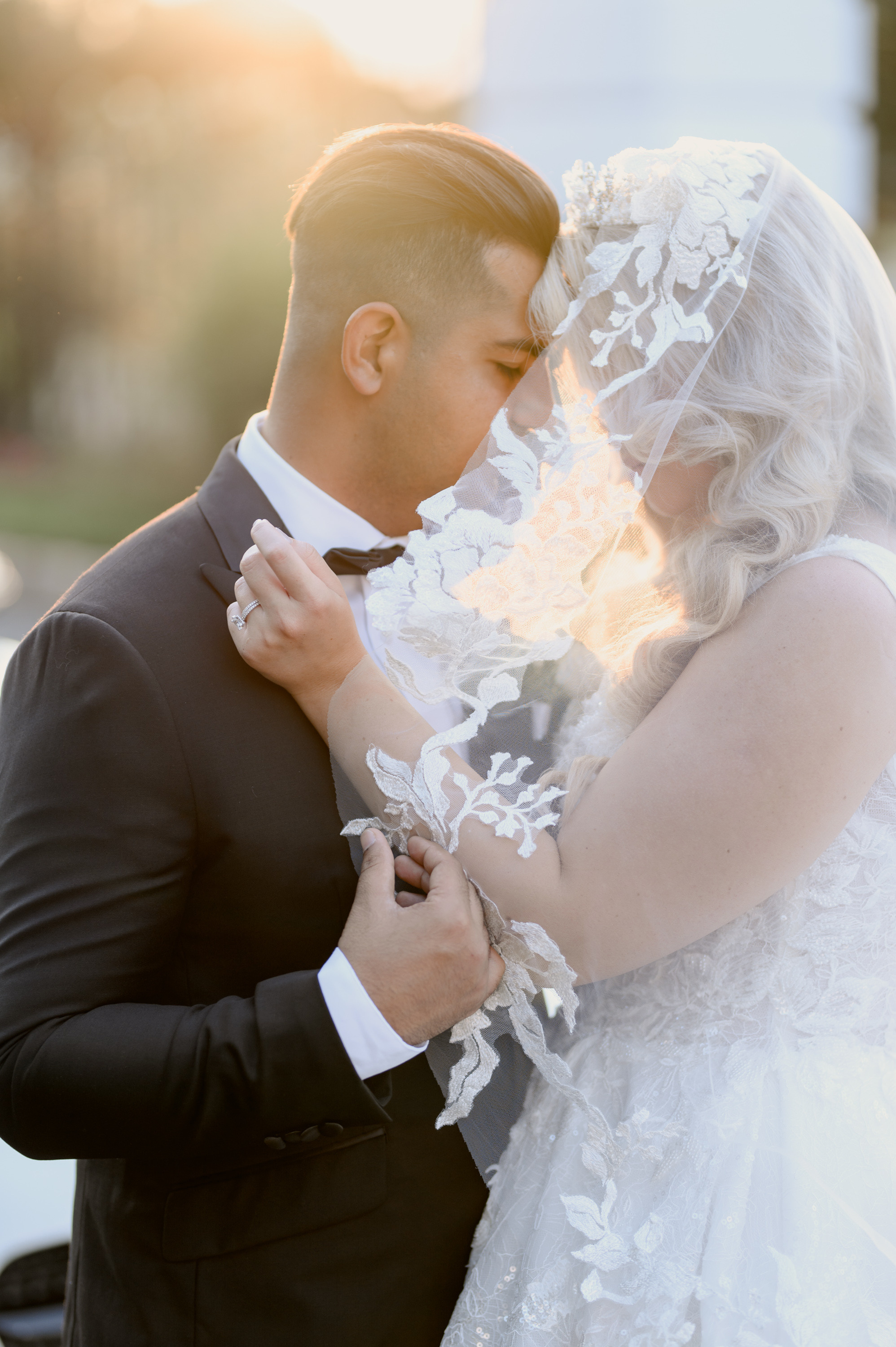 a bride and groom kissing in front of a car
