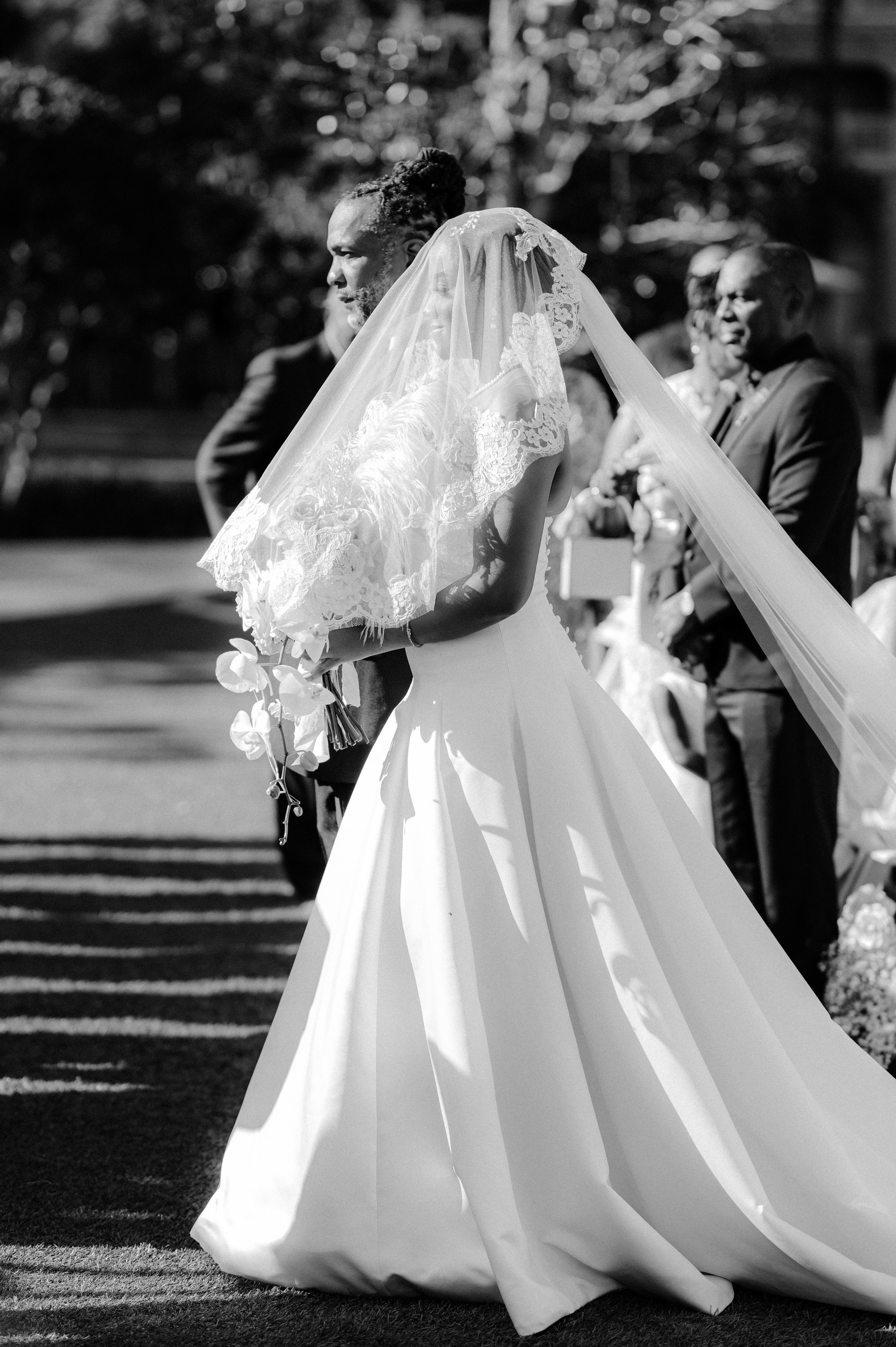a bride walking down the aisle with her veil blowing in the wind