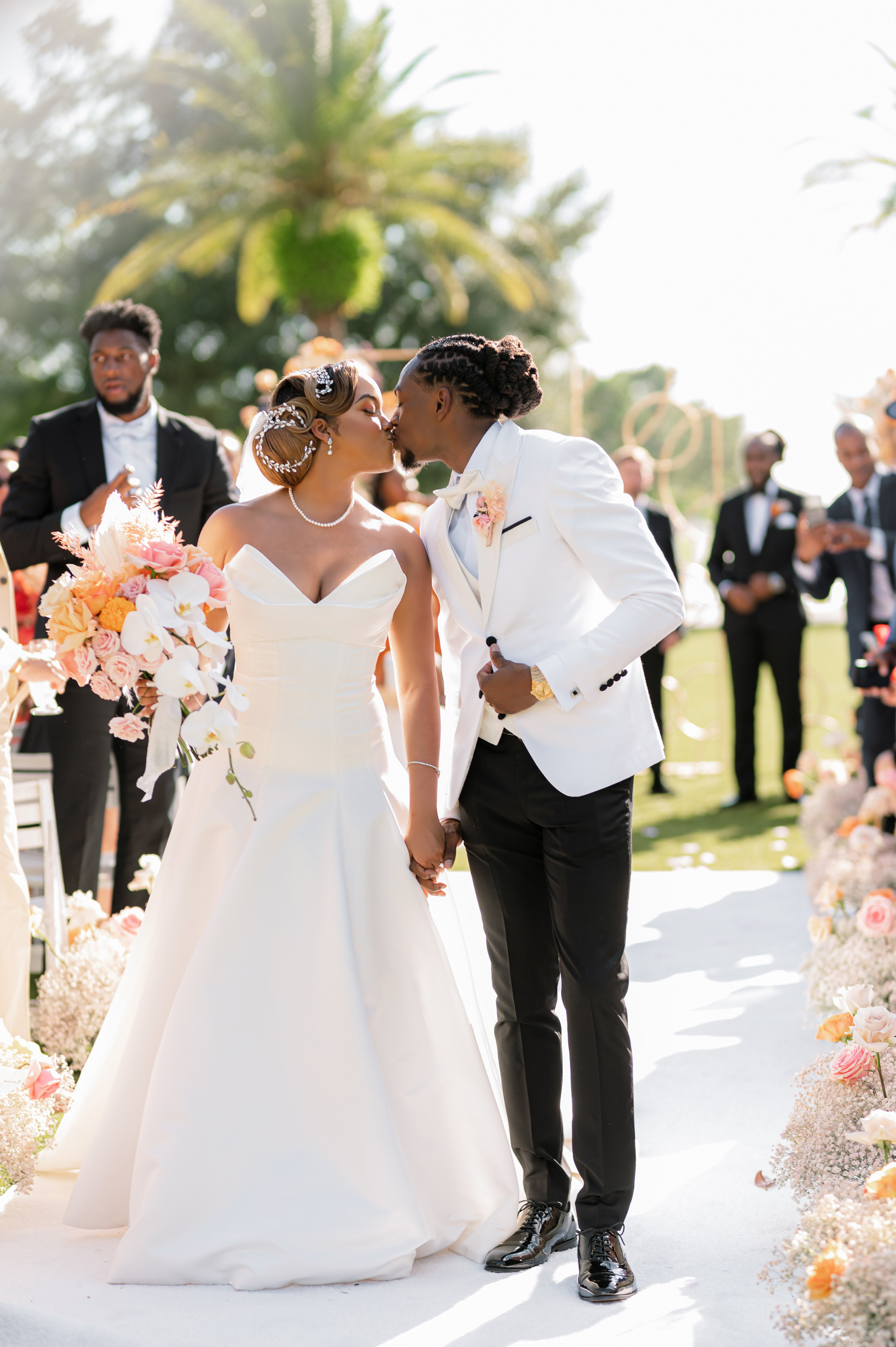 a bride and groom kissing in front of a wedding party