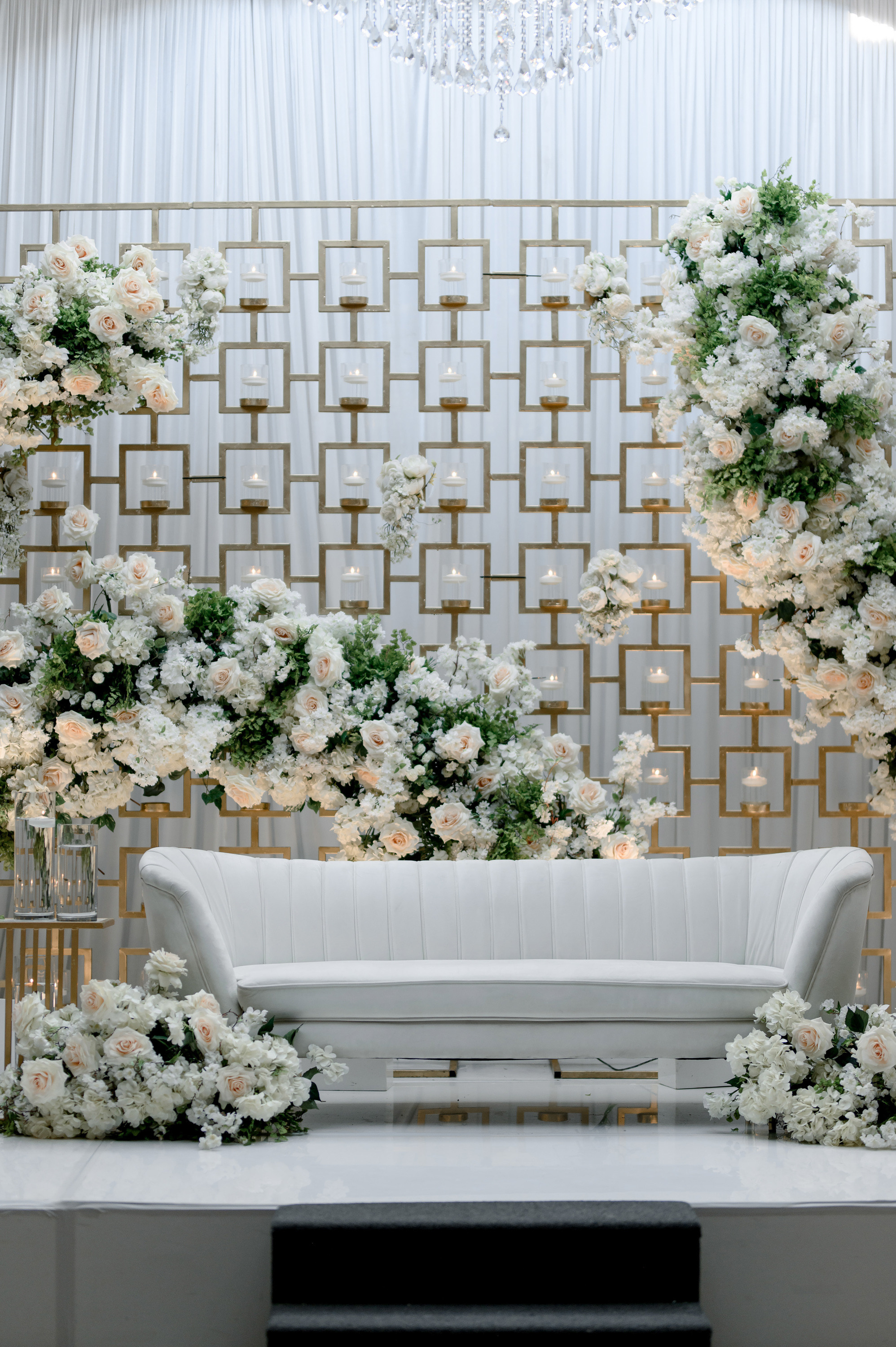a white couch with a white and gold wedding arch