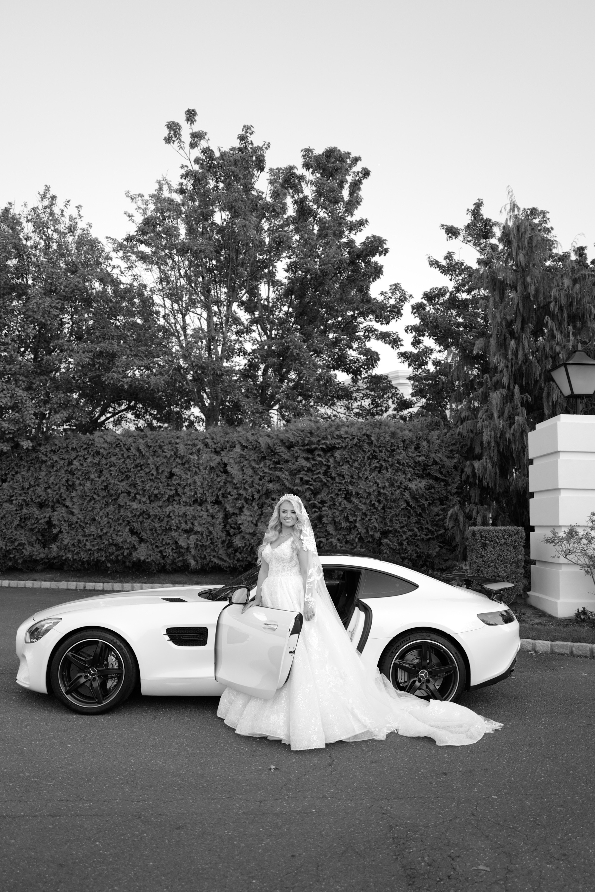 a bride poses with her white sports car