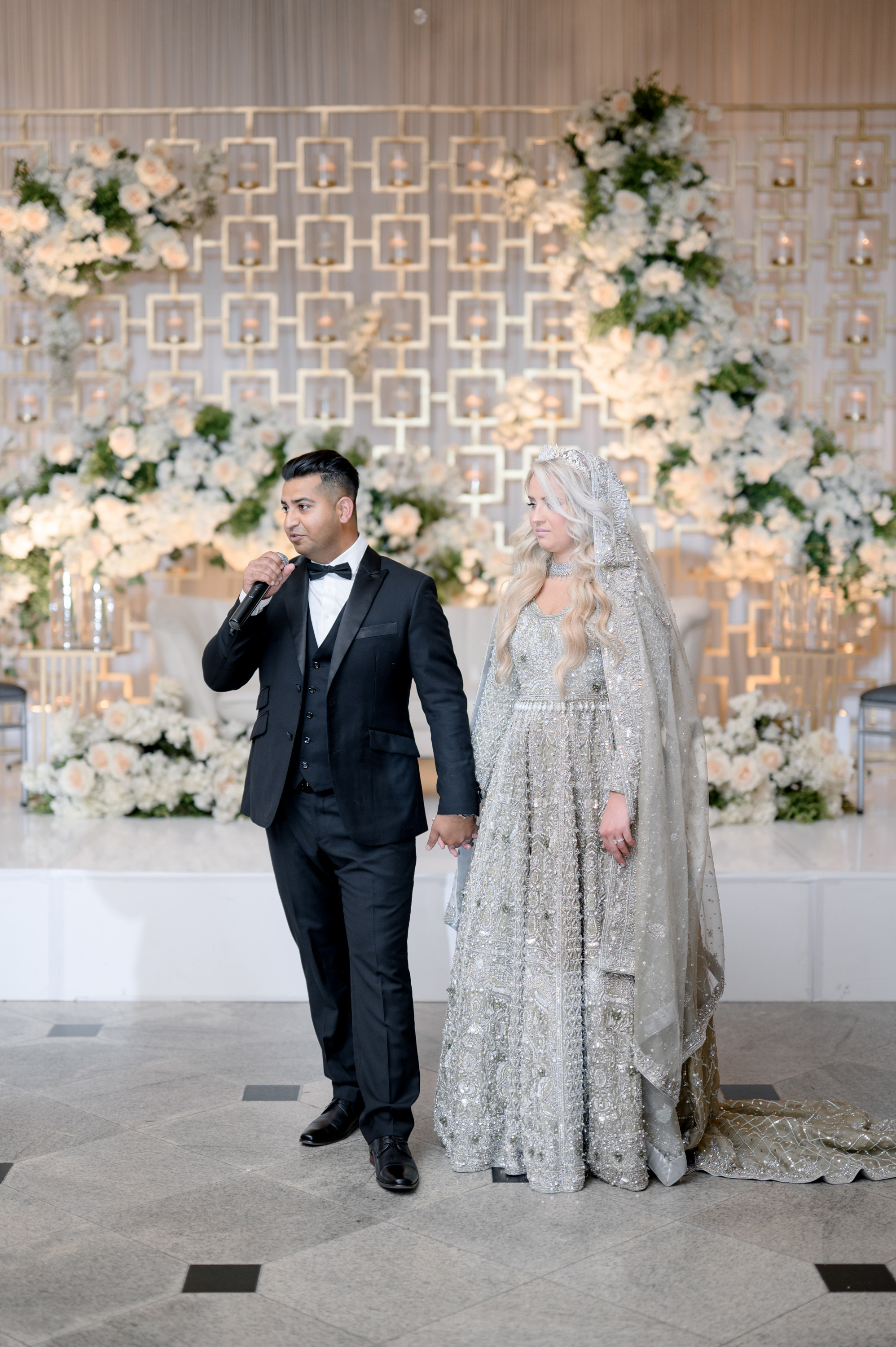 a bride and groom standing in front of a floral wall