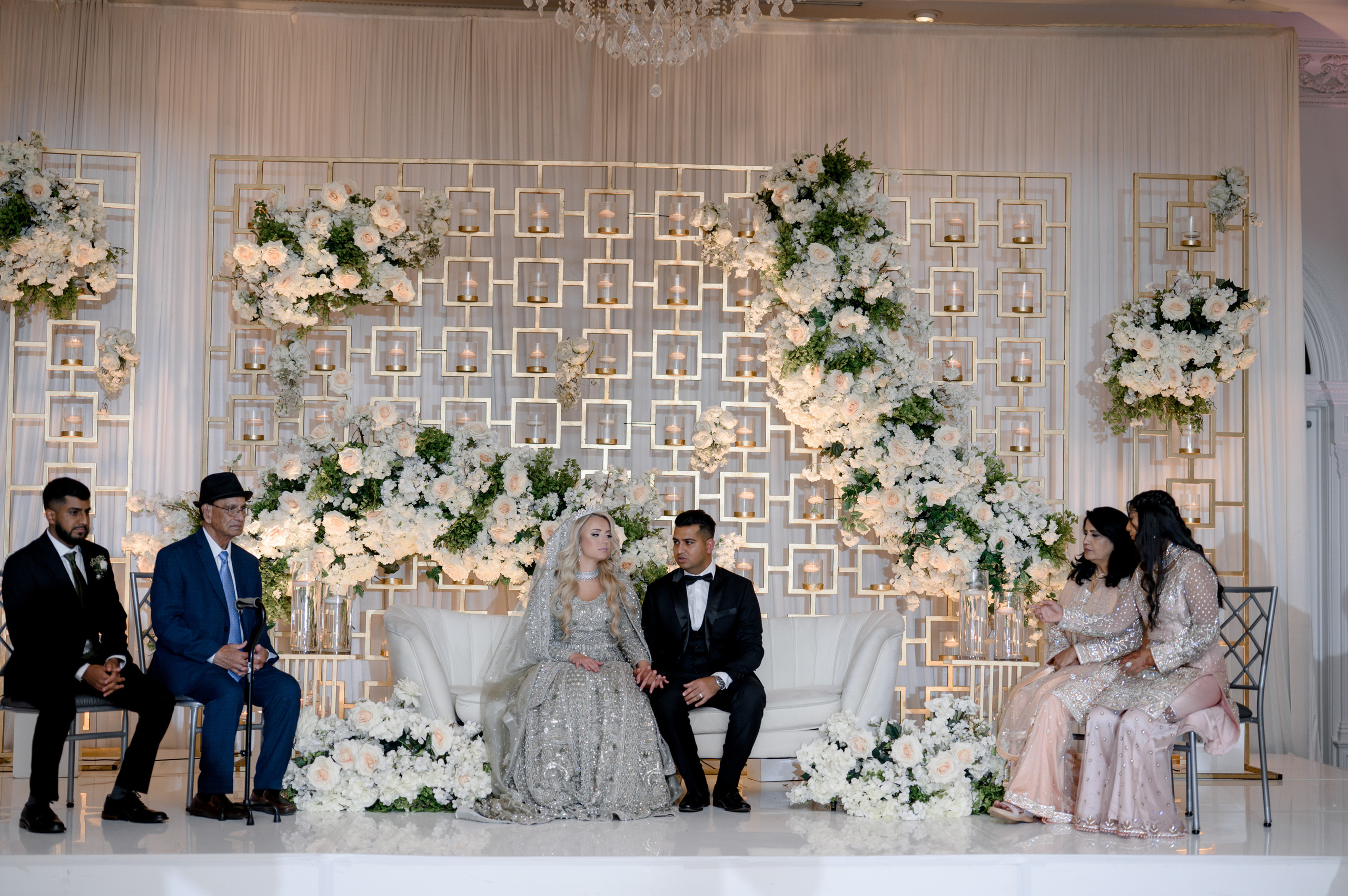 a couple sitting on a couch in front of a wedding ceremony
