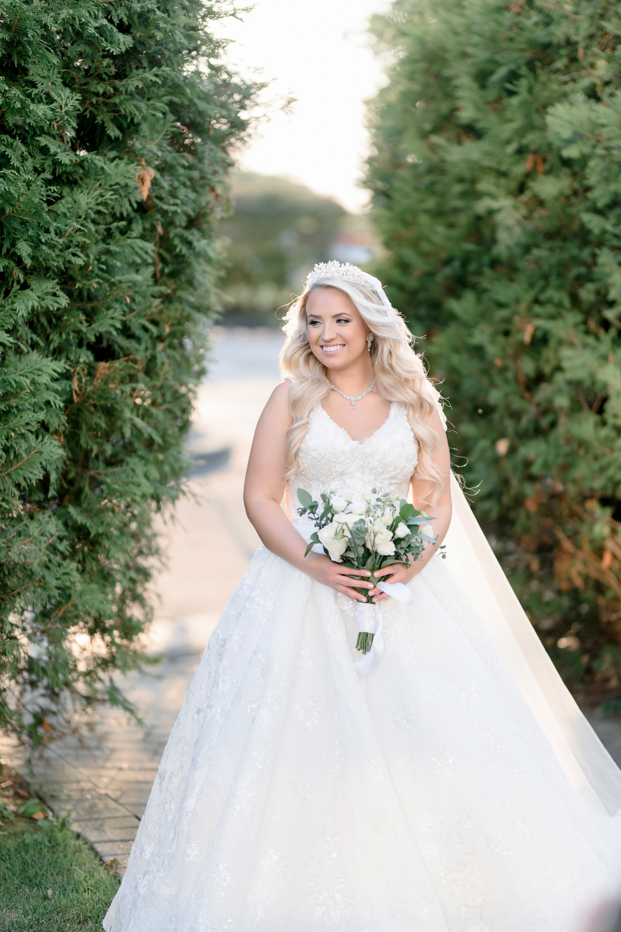 a bride in a white dress and veil poses for a photo
