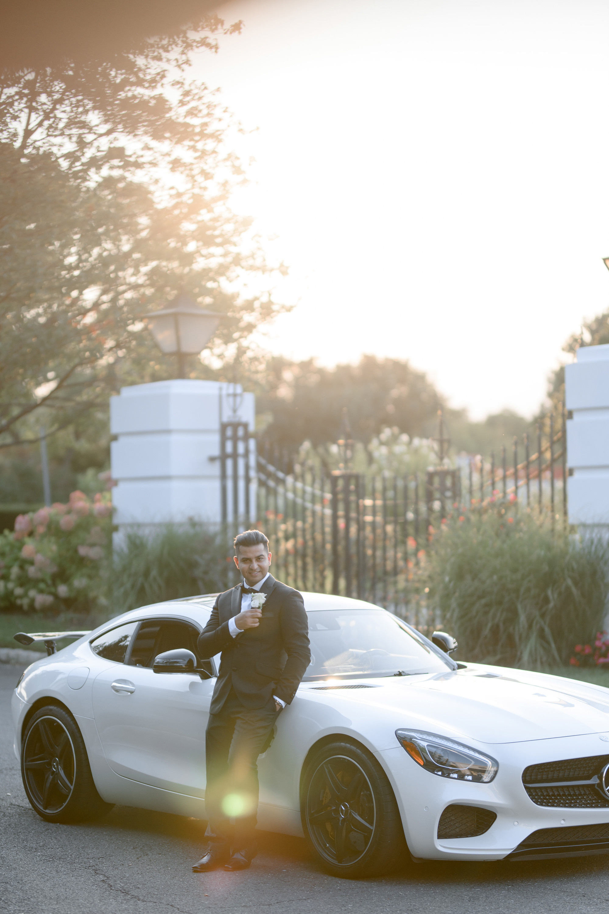 a man in a suit standing next to a white sports car