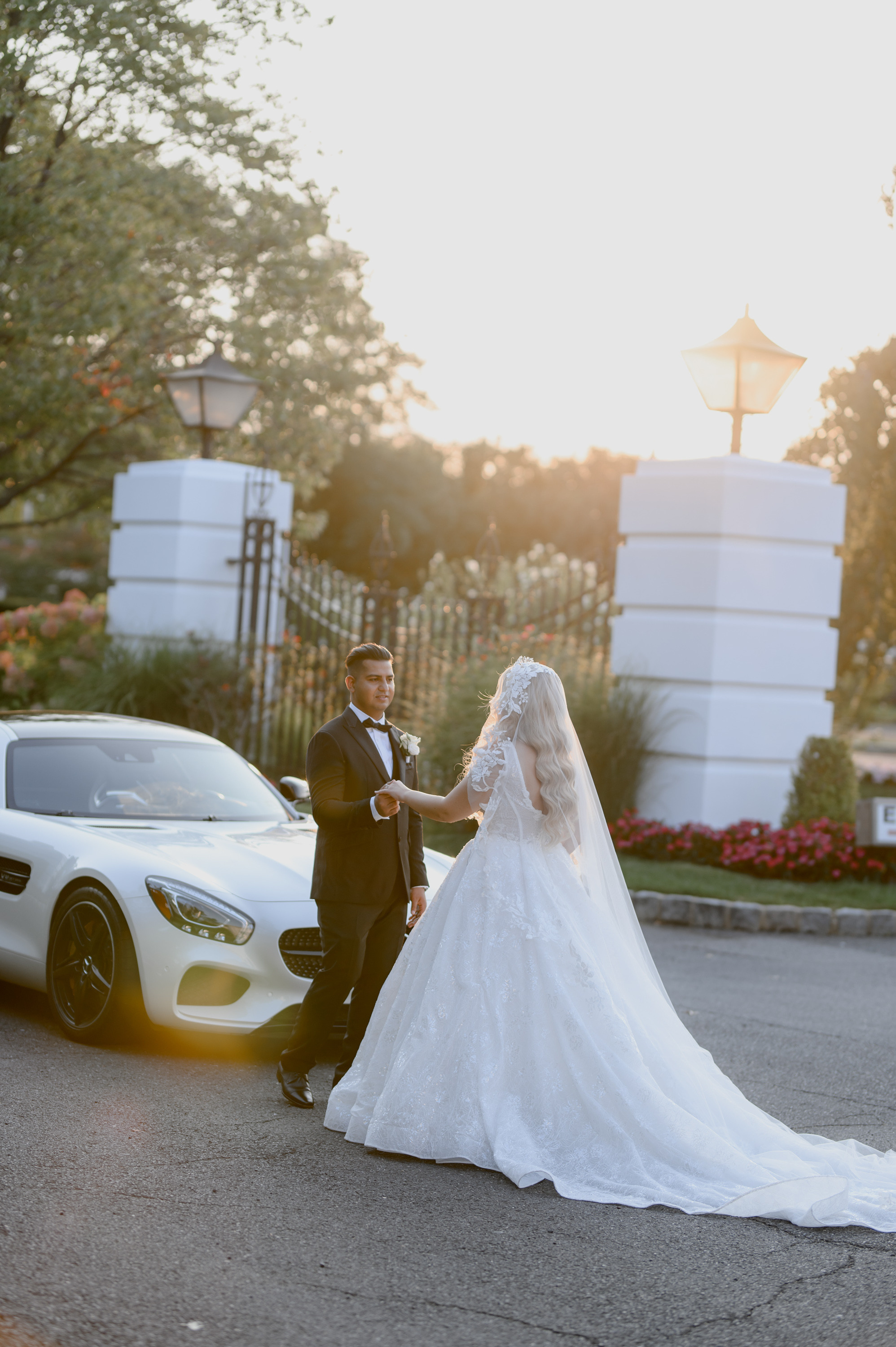 a bride and groom pose for a photo in front of a white car