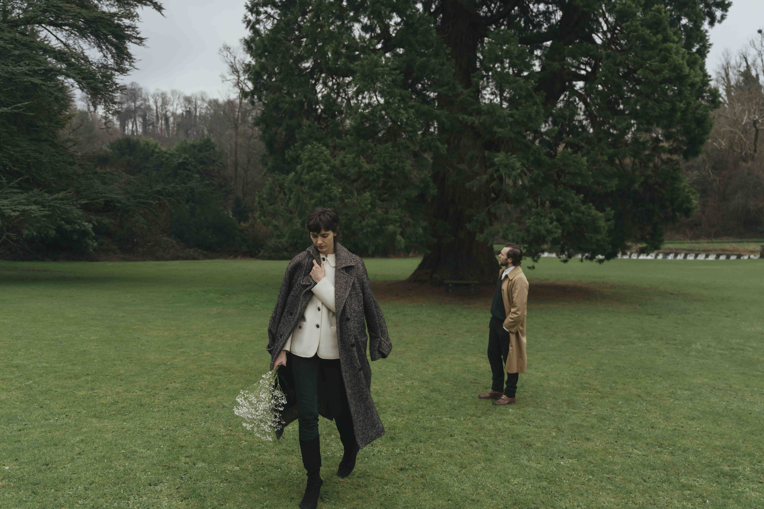 cinematic couple walking through green countryside landscape in Cotswolds engagement session